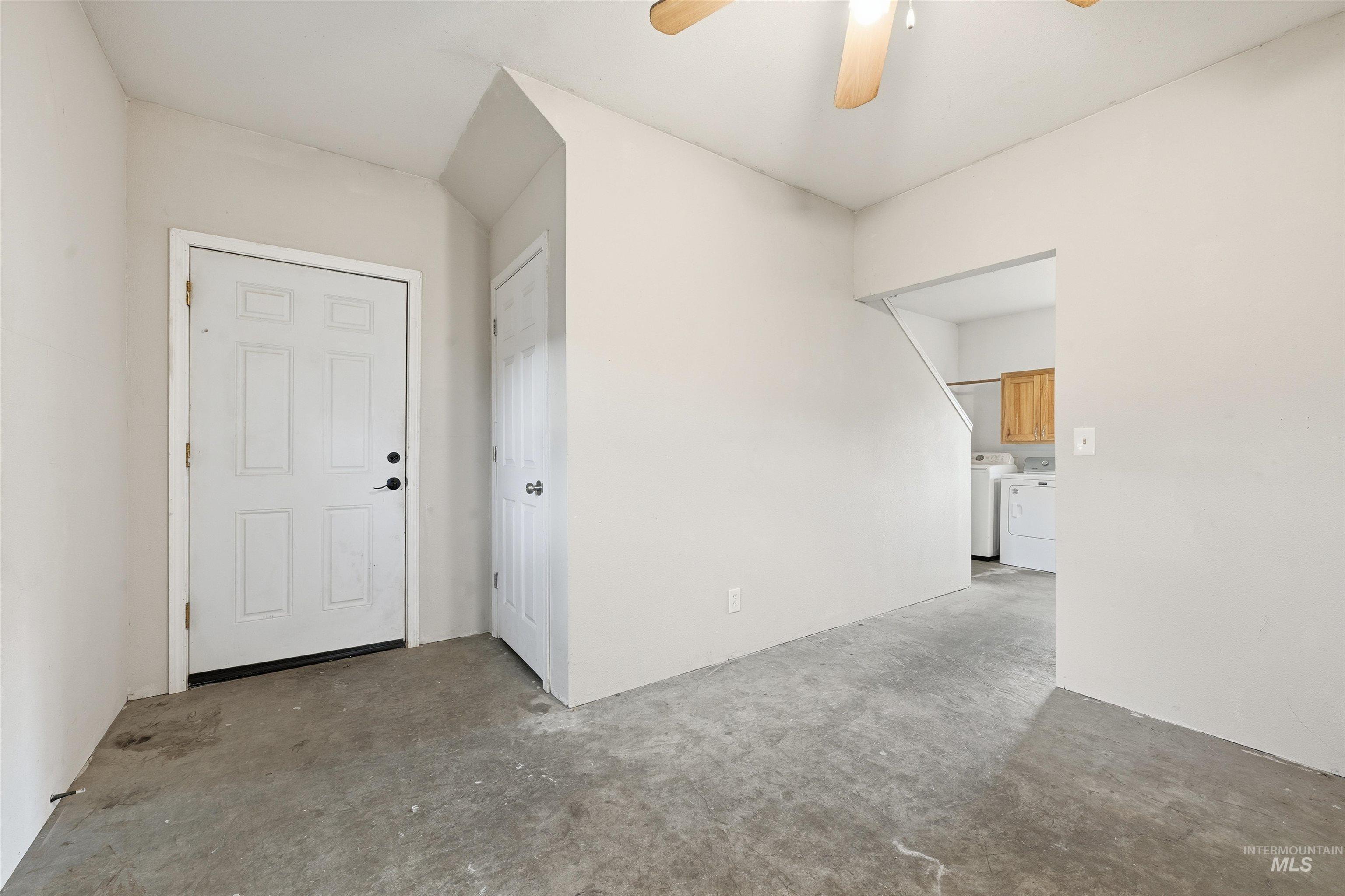 Unfurnished room with concrete floors, a ceiling fan, and washer and dryer
