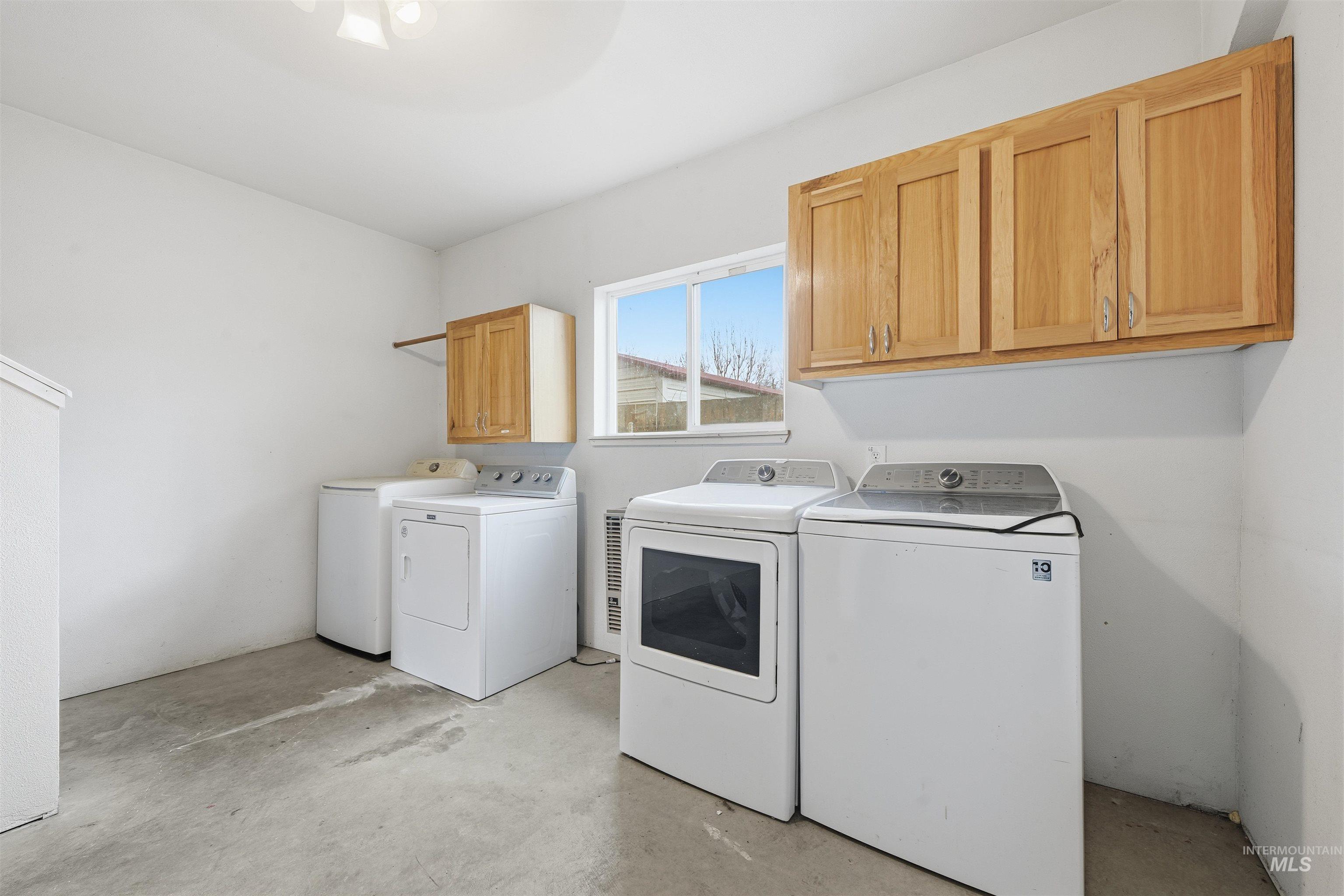 Washroom with cabinet space, independent washer and dryer, and unfinished concrete floors