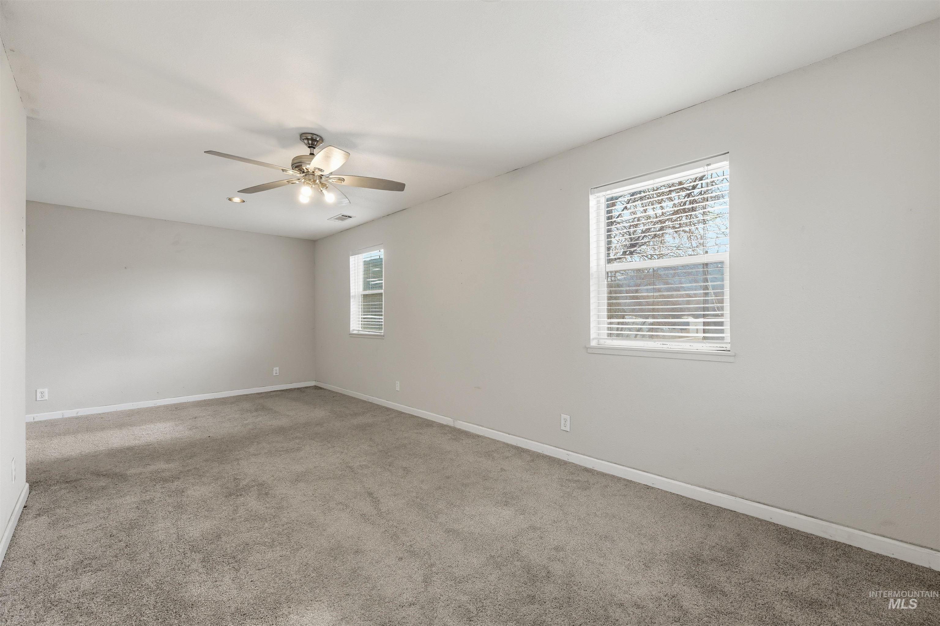 Empty room with light colored carpet and a ceiling fan