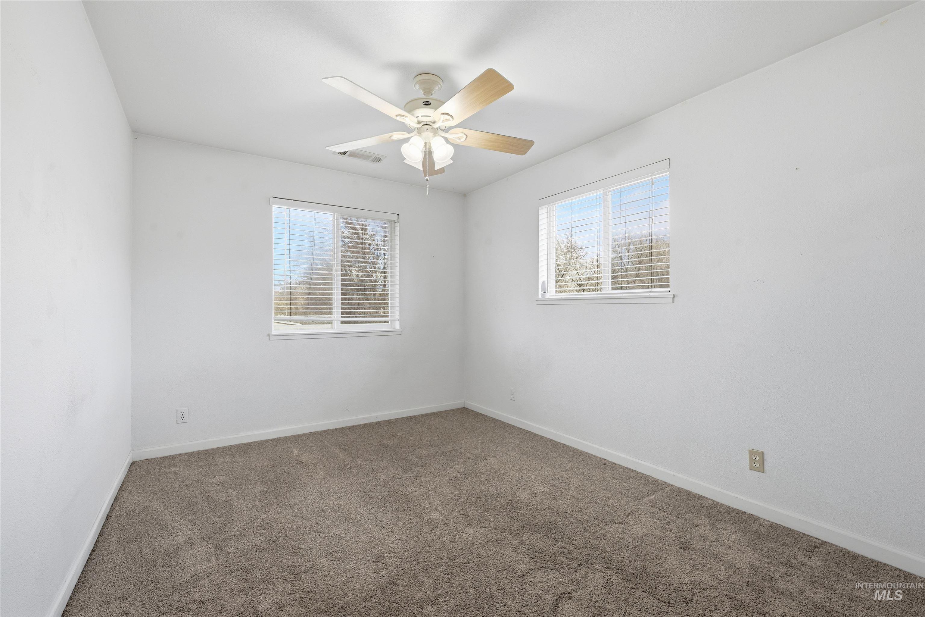Carpeted spare room with plenty of natural light and a ceiling fan
