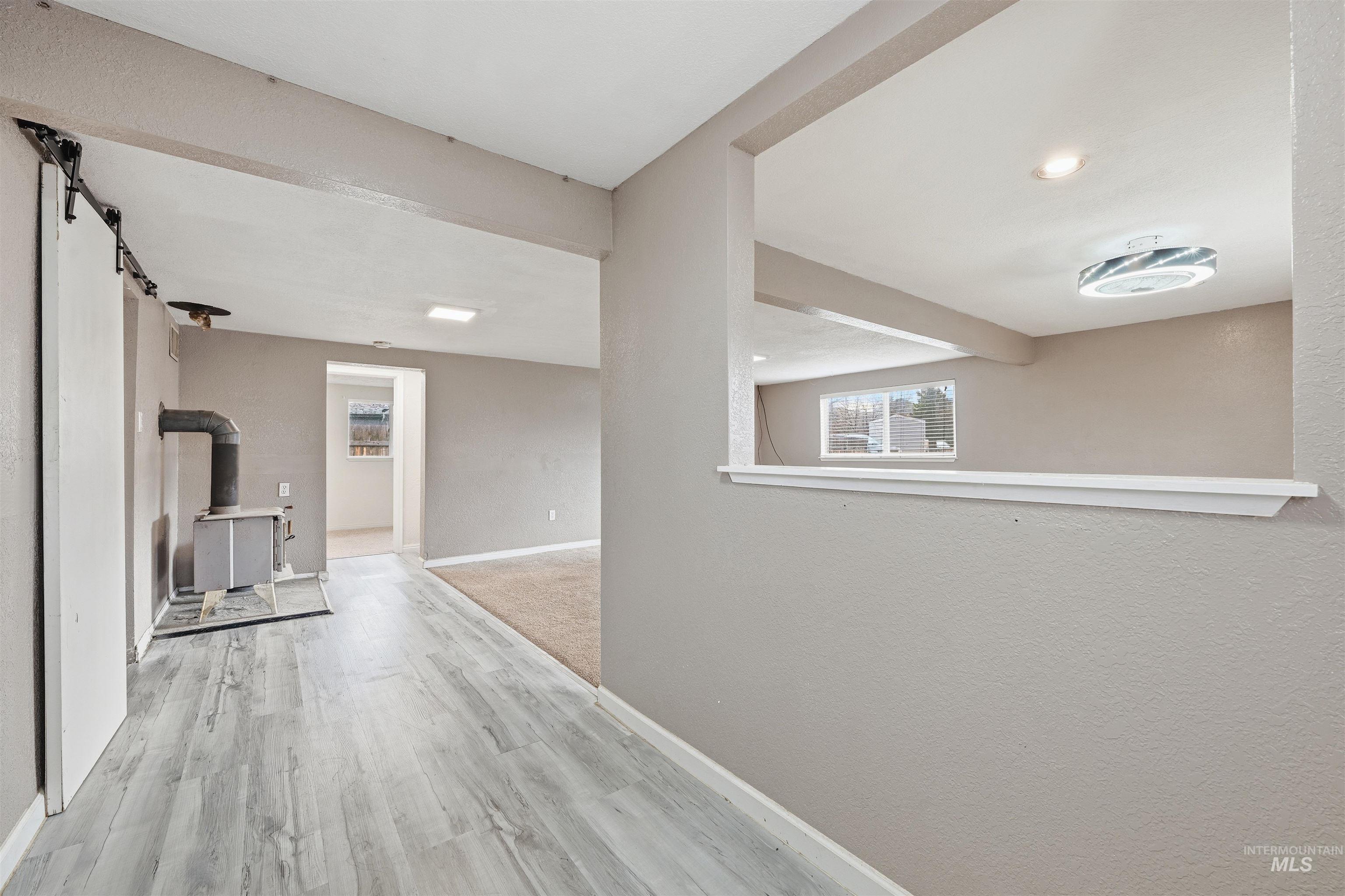 Hallway featuring light wood-style floors, a barn door, a textured wall, and recessed lighting