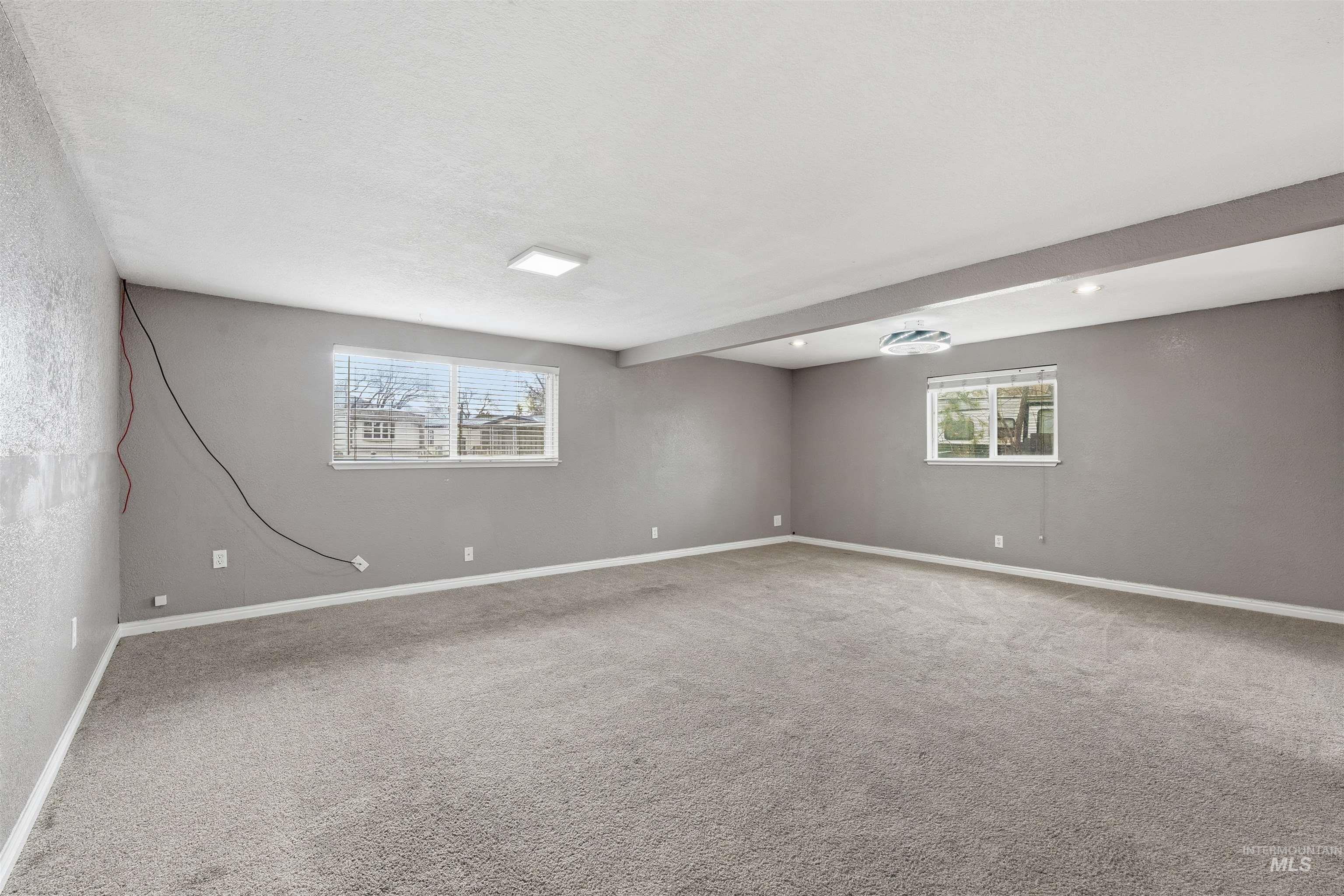 Unfurnished room featuring carpet floors and beamed ceiling