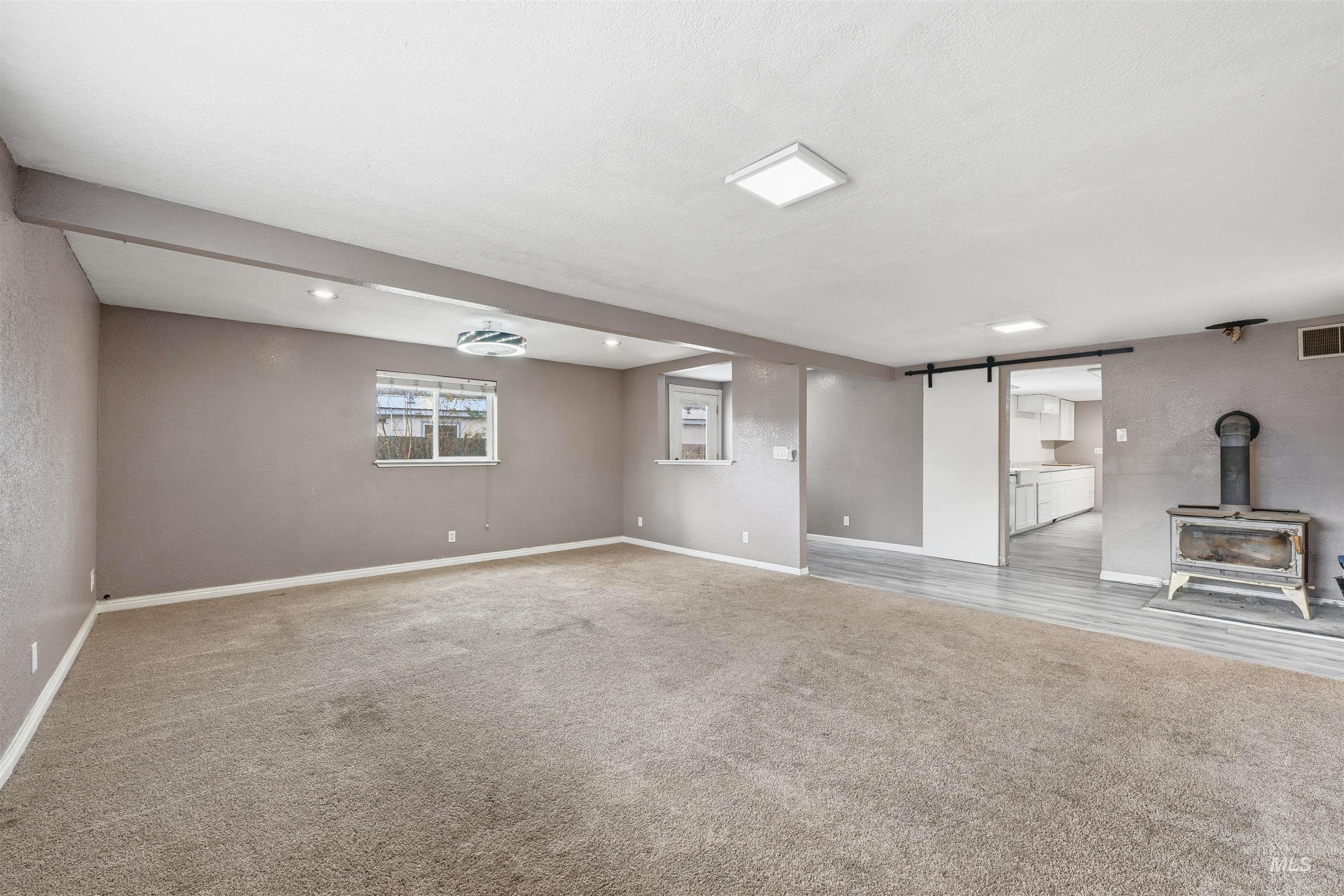 Basement featuring a barn door, light carpet, a wood stove, and recessed lighting