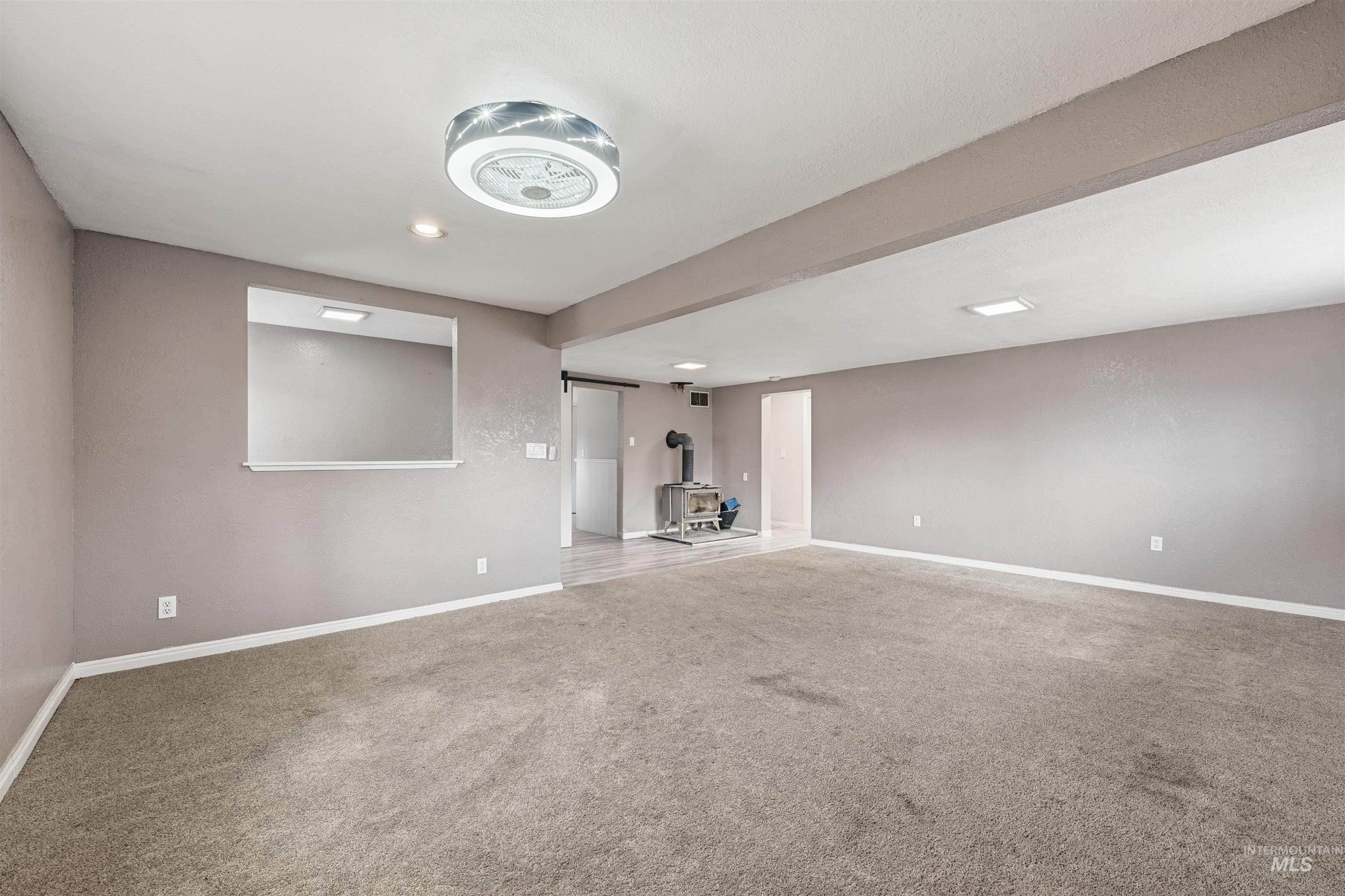 Carpeted empty room featuring a wood stove and recessed lighting