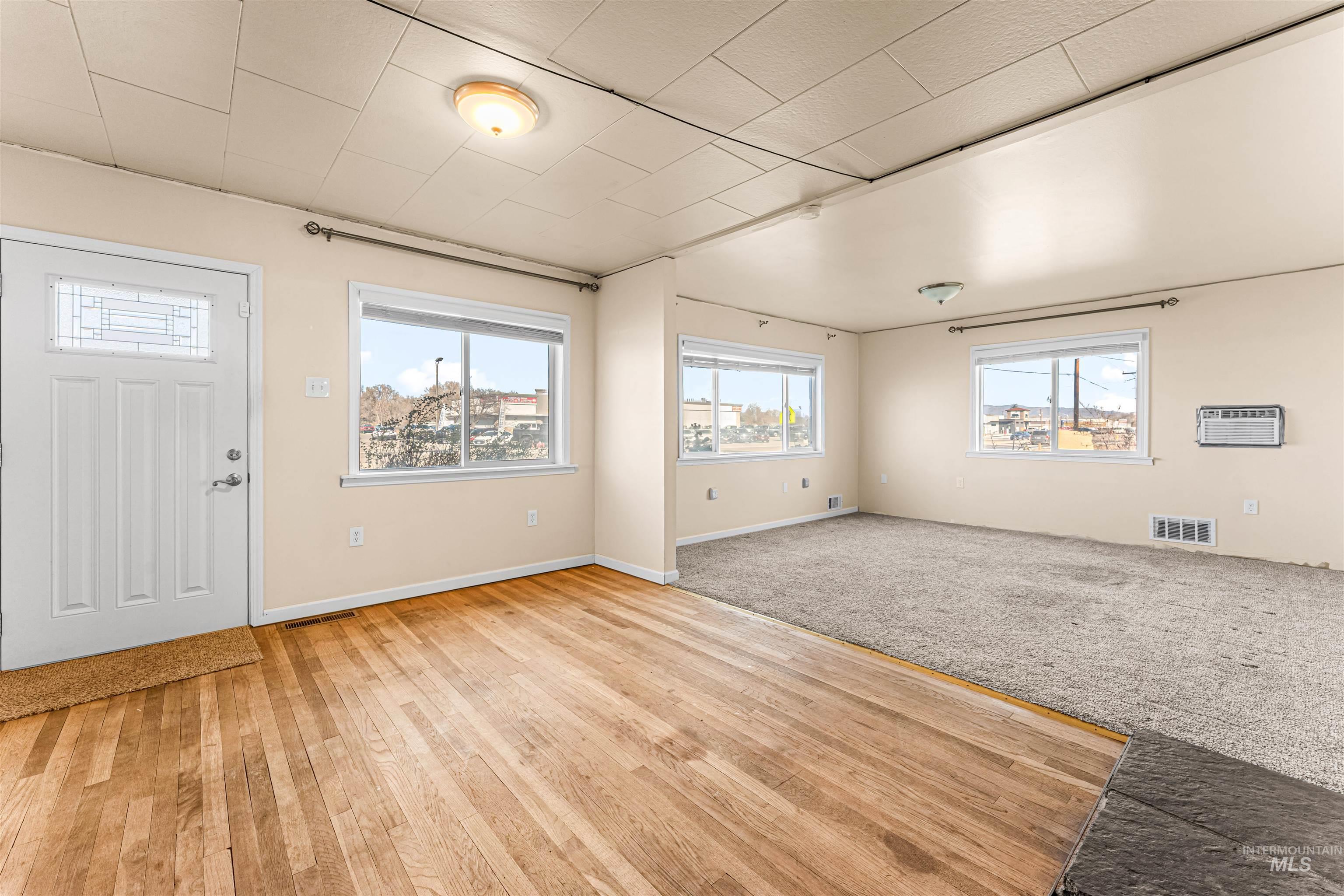 Entryway with light colored carpet and a wall unit AC