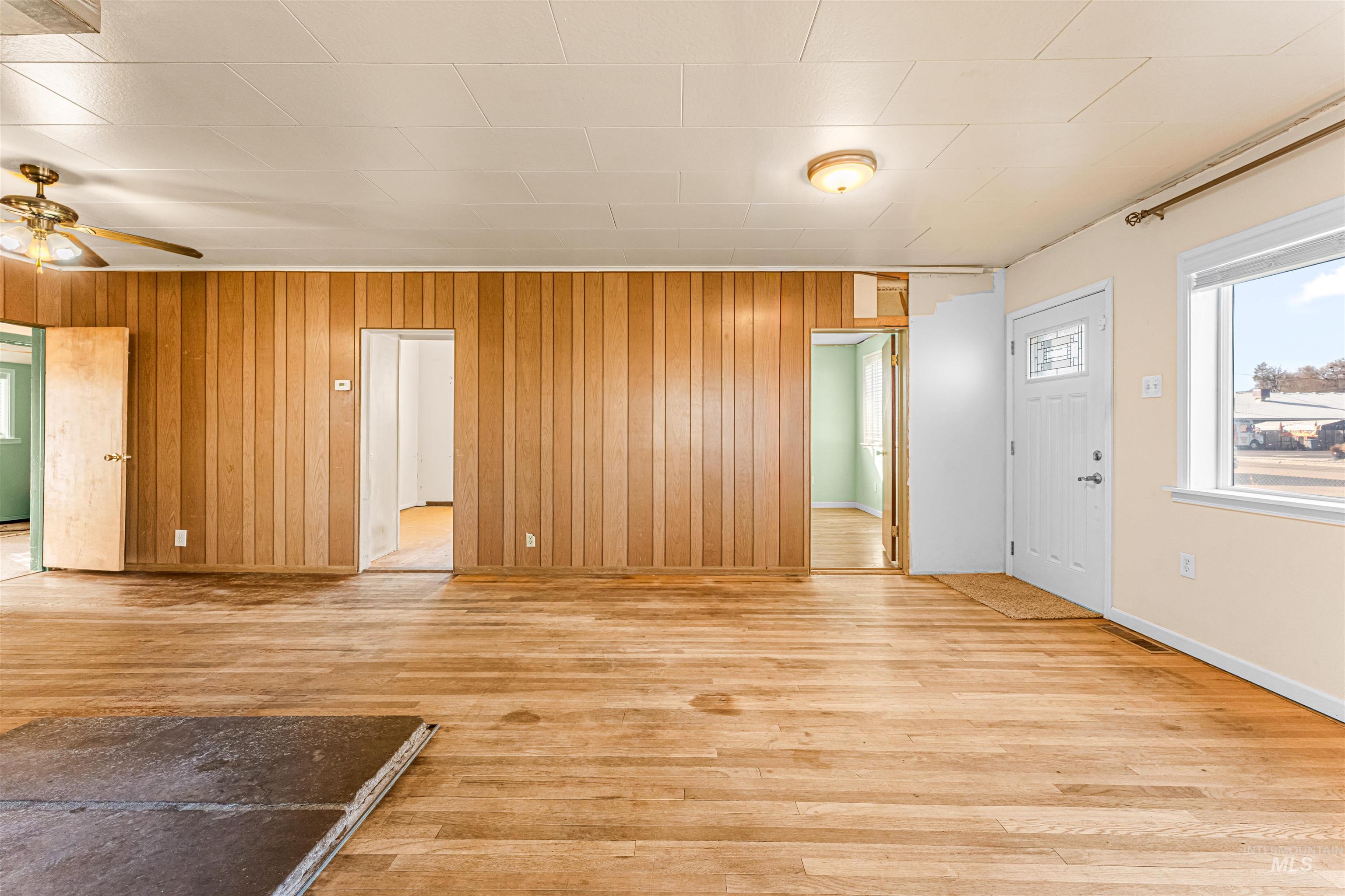 Entryway featuring light wood-style floors, wooden walls, and ceiling fan