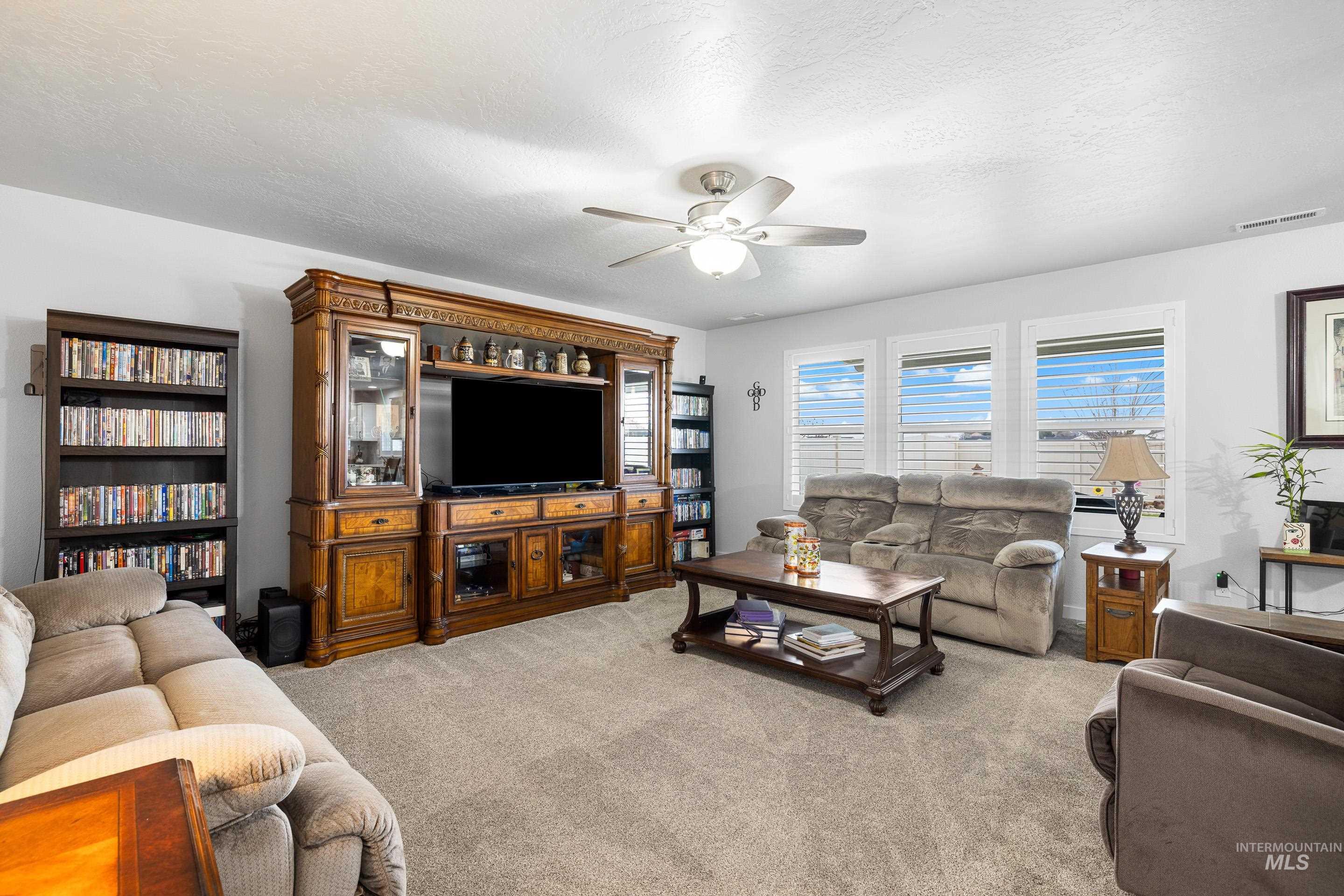 Living area featuring a textured ceiling, light carpet, and ceiling fan