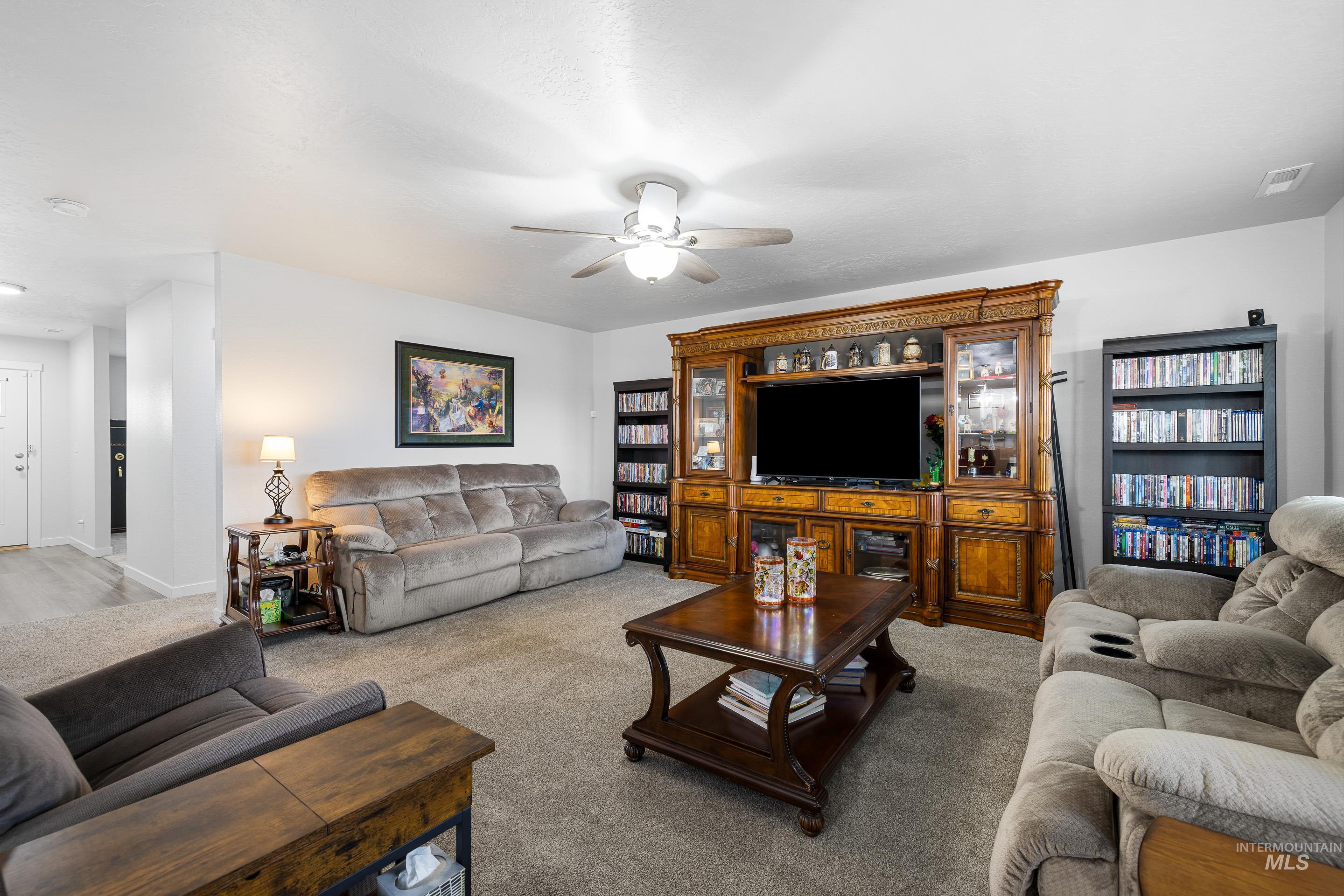 Living room with a ceiling fan and light colored carpet