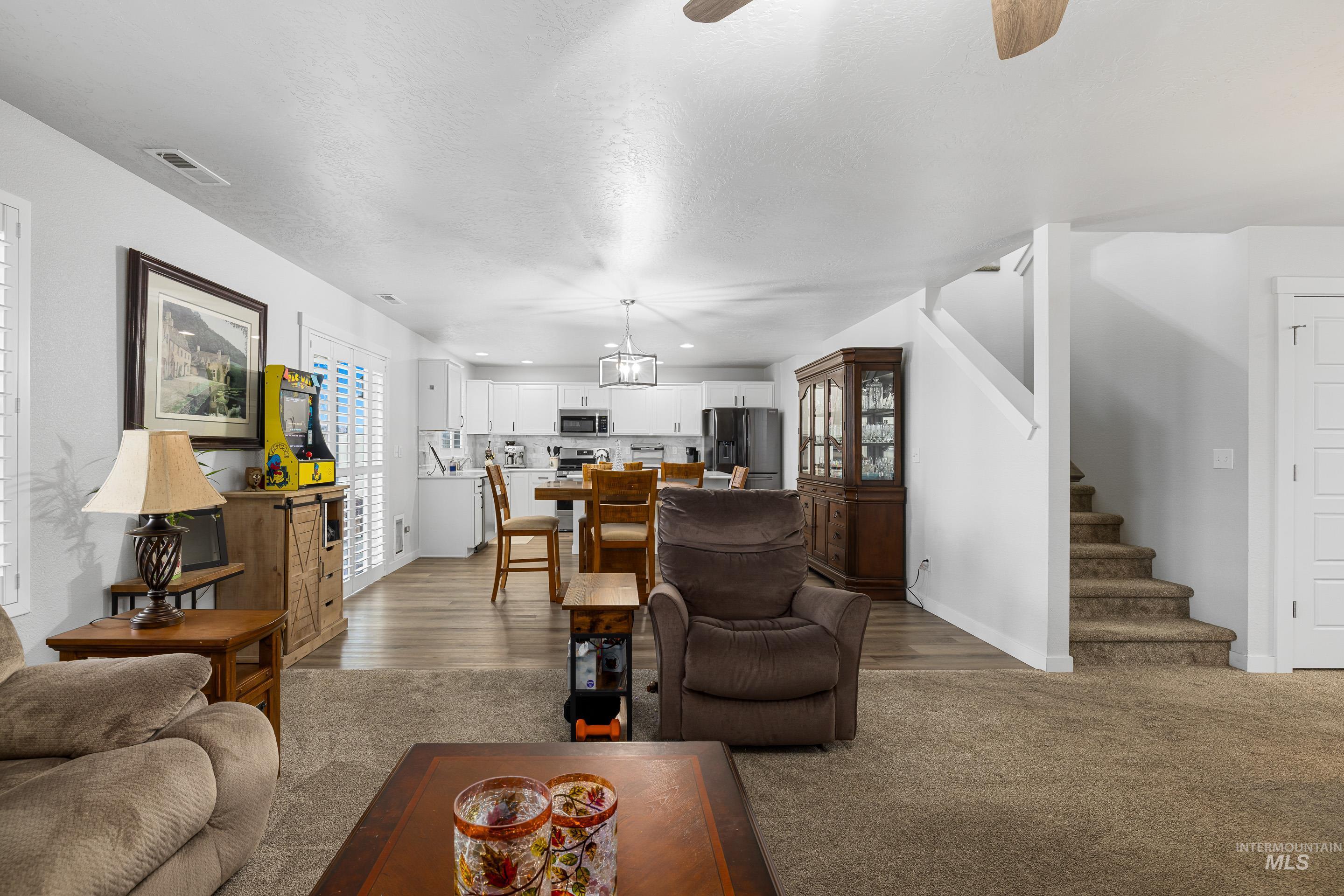 Carpeted living room featuring ceiling fan, stairway, recessed lighting, and a textured ceiling