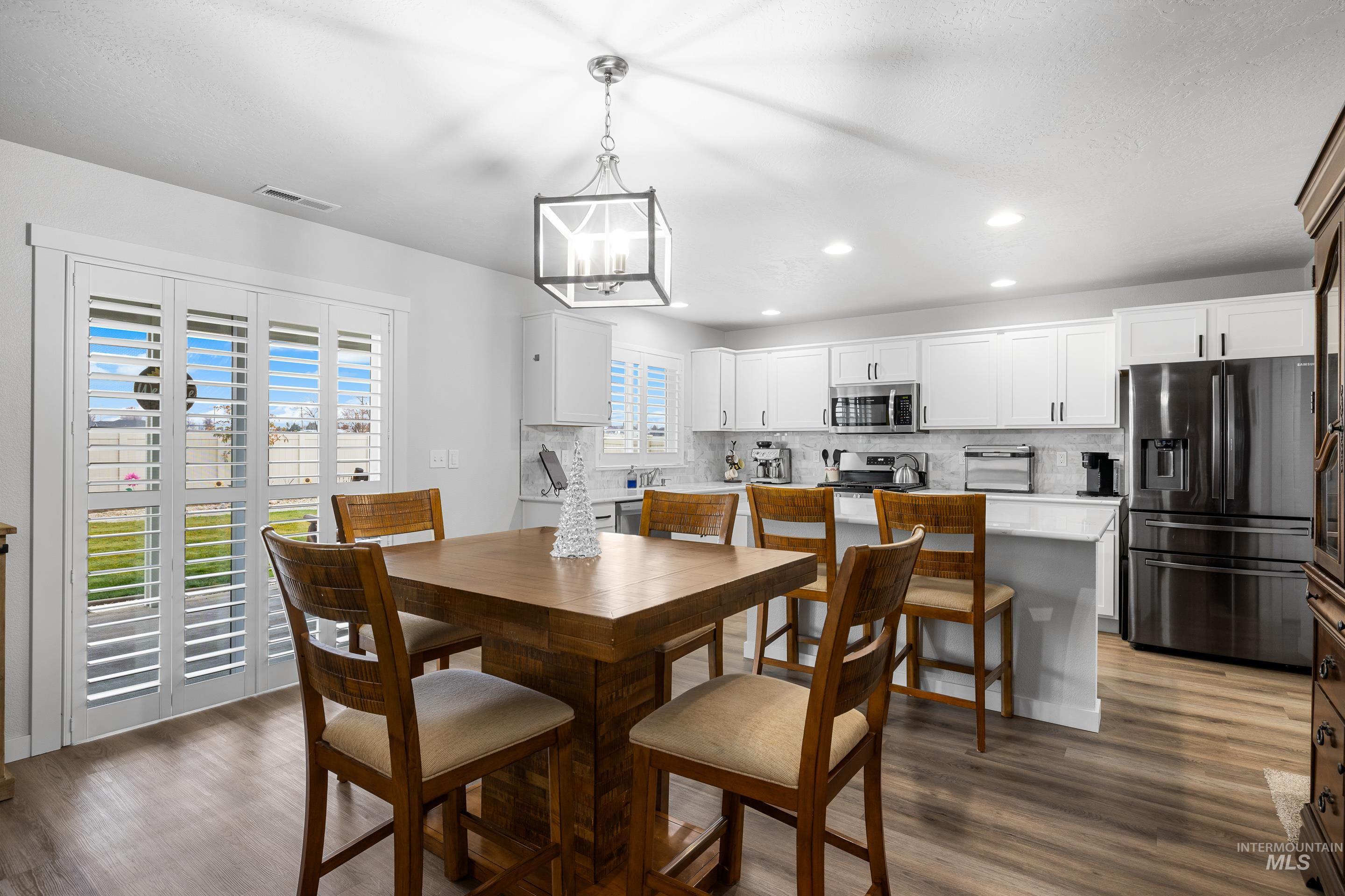 Dining space with dark wood-type flooring, recessed lighting, and a chandelier