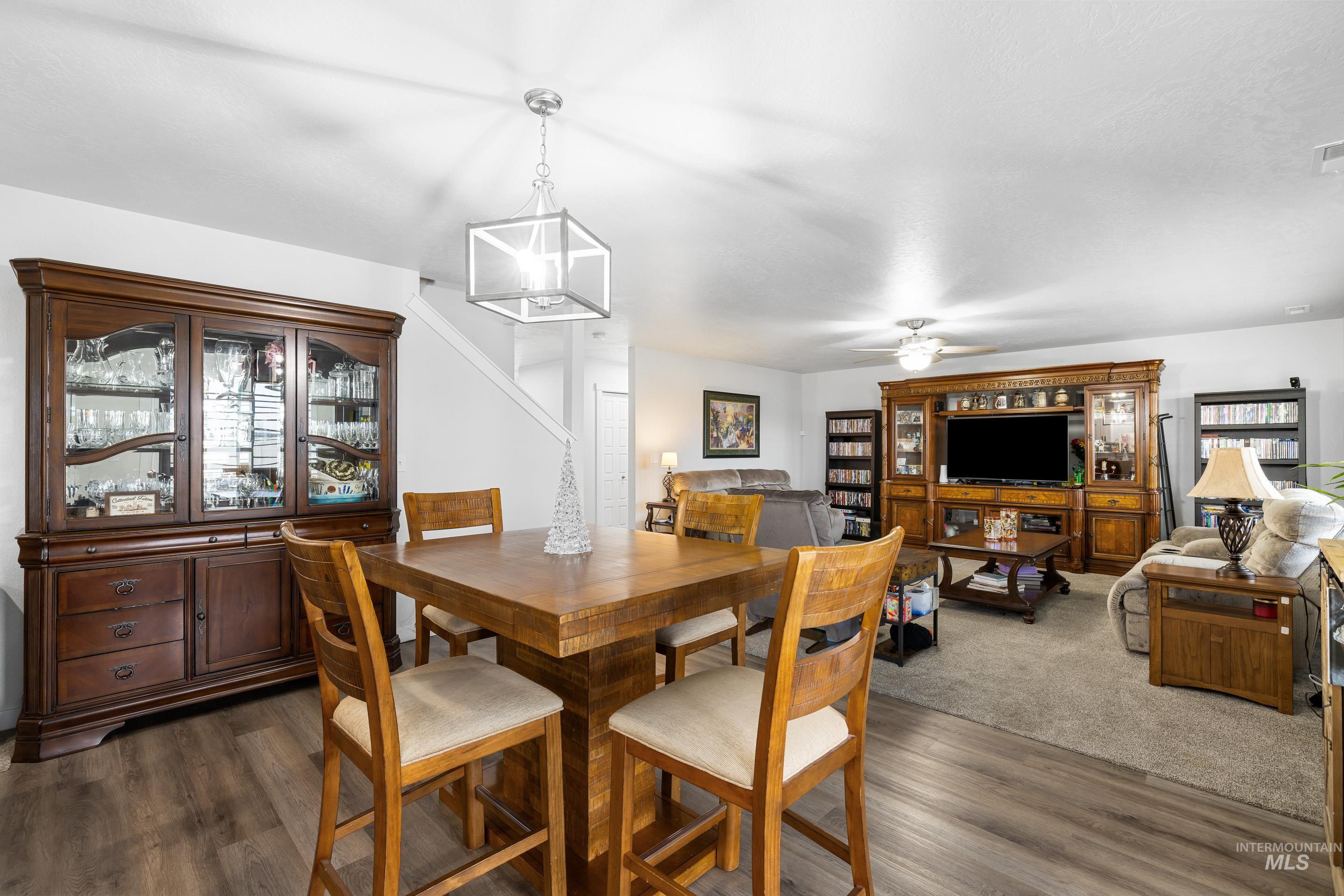 Dining space featuring dark wood-type flooring, ceiling fan, and a chandelier