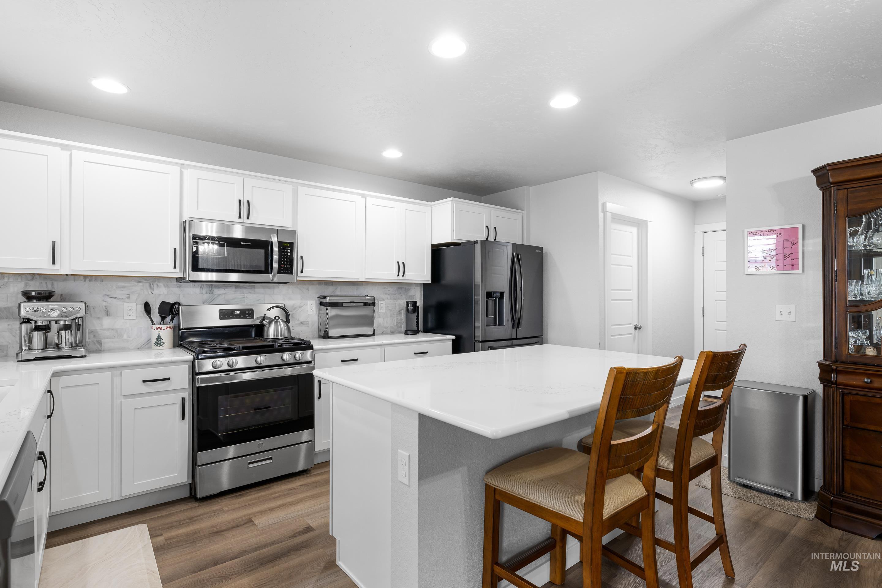 Kitchen featuring appliances with stainless steel finishes, a center island, a breakfast bar area, white cabinets, and recessed lighting