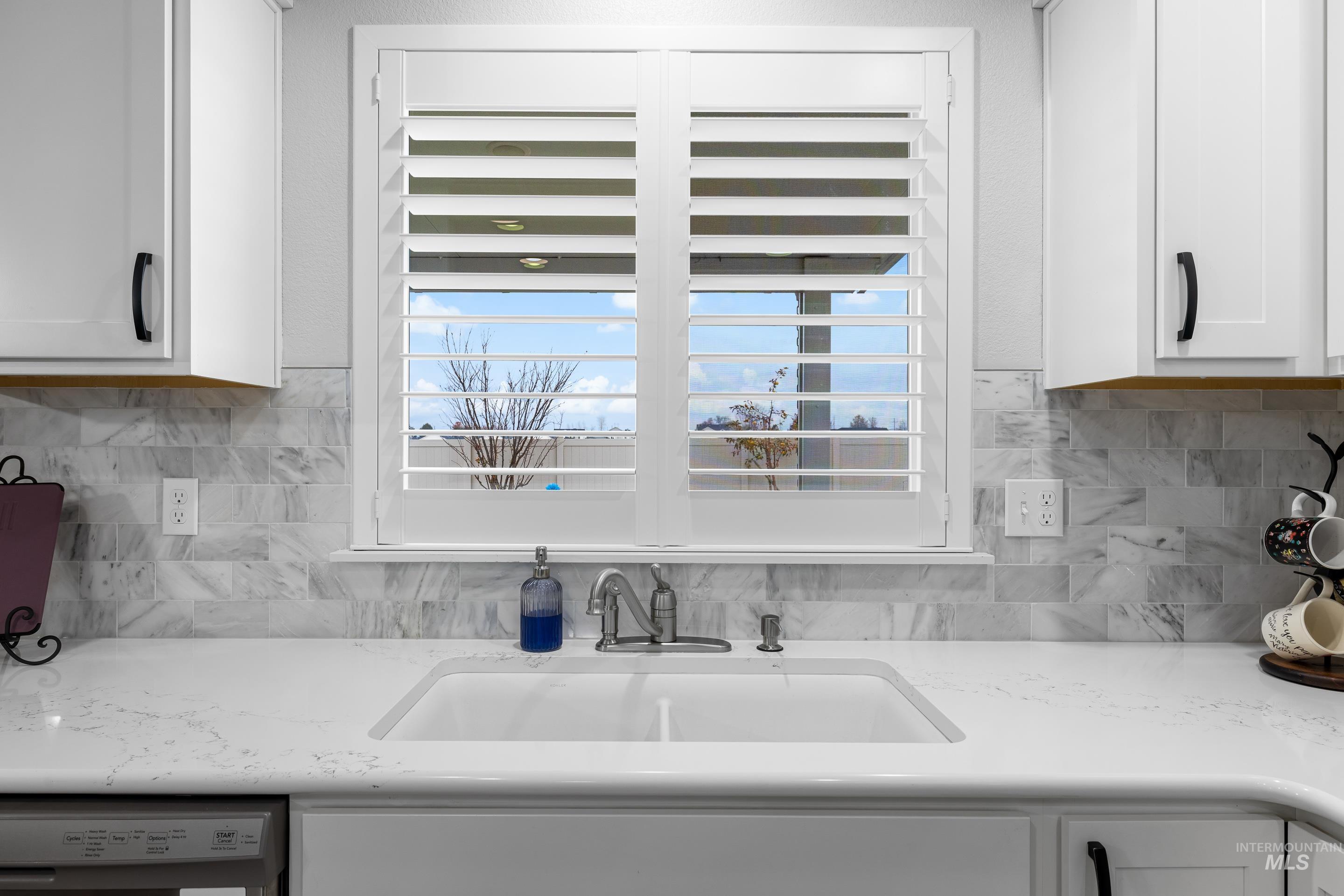 Kitchen with white cabinetry, tasteful backsplash, and light stone countertops