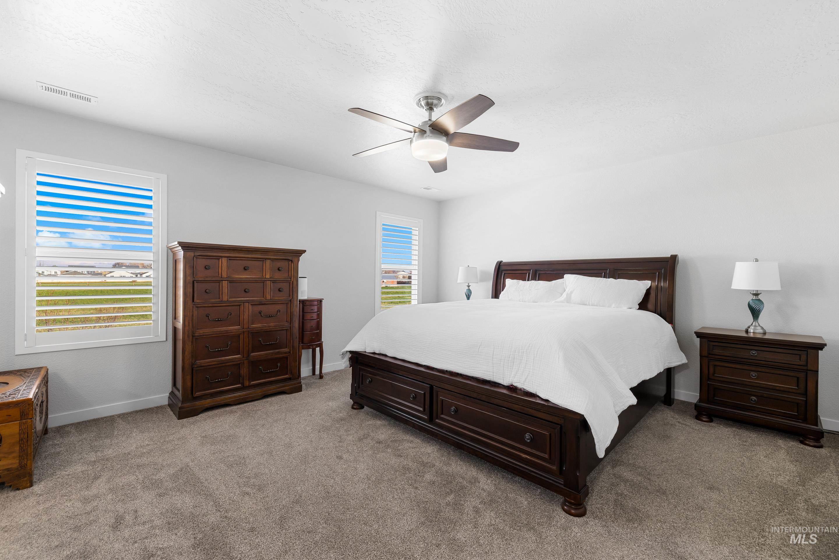 Carpeted bedroom with a ceiling fan and baseboards
