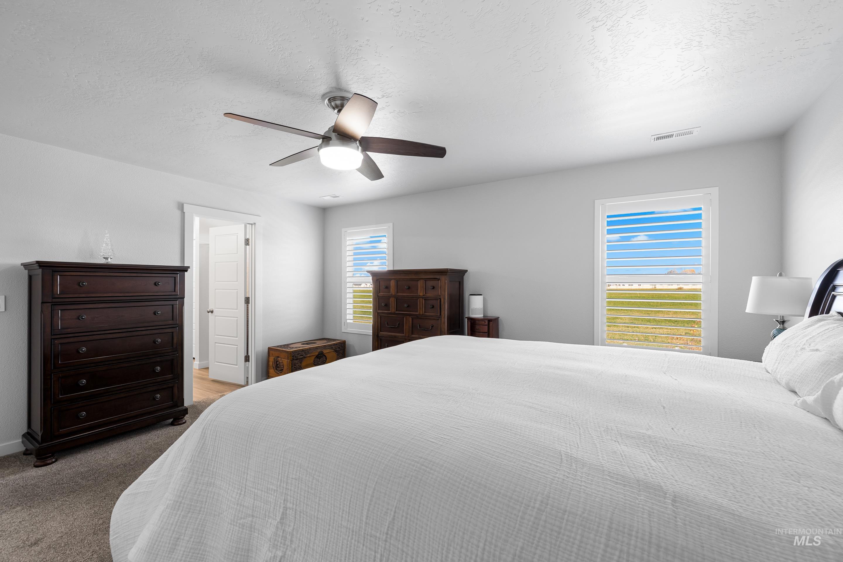 Bedroom featuring a textured ceiling, carpet floors, and ceiling fan