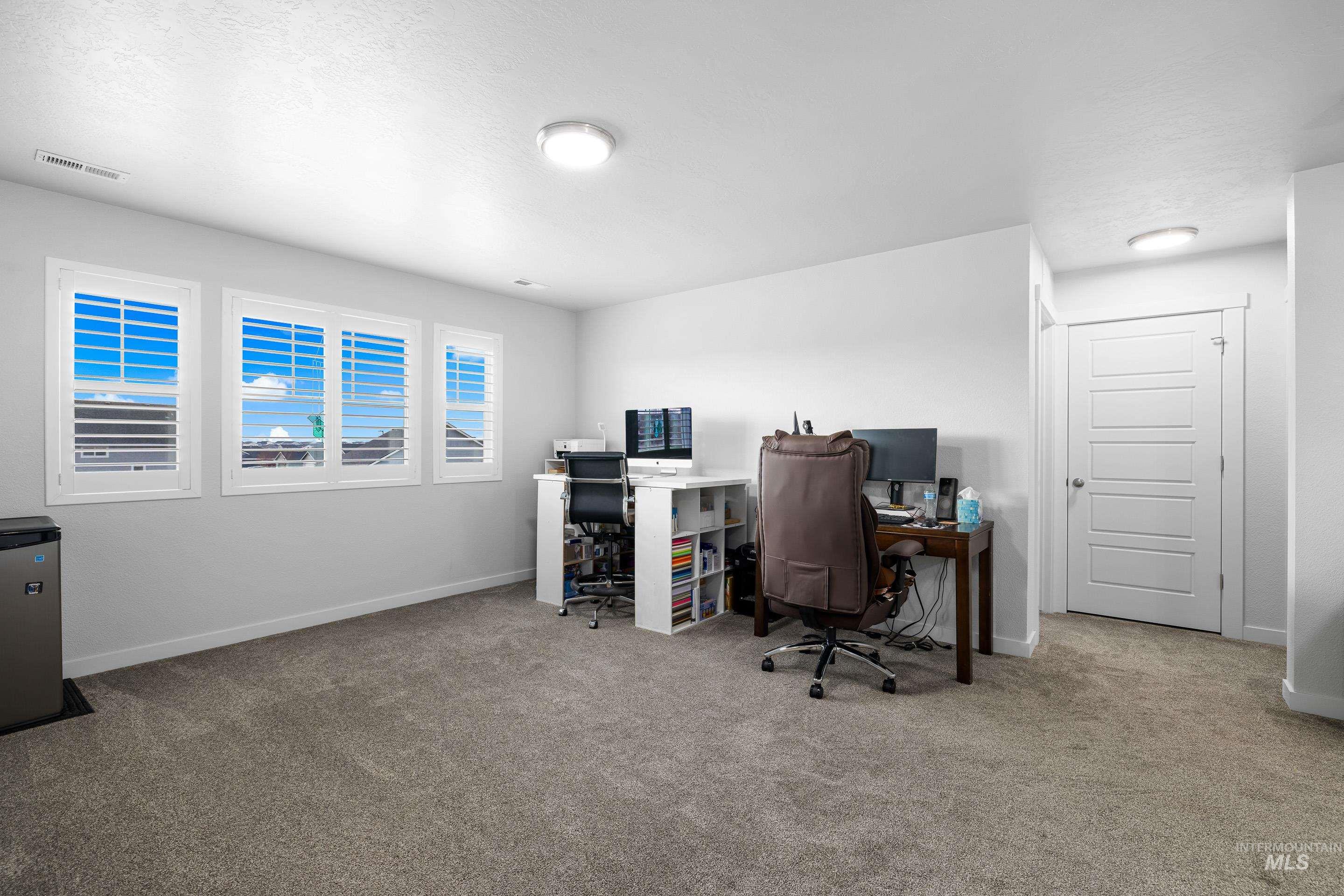 Home office featuring light carpet and baseboards