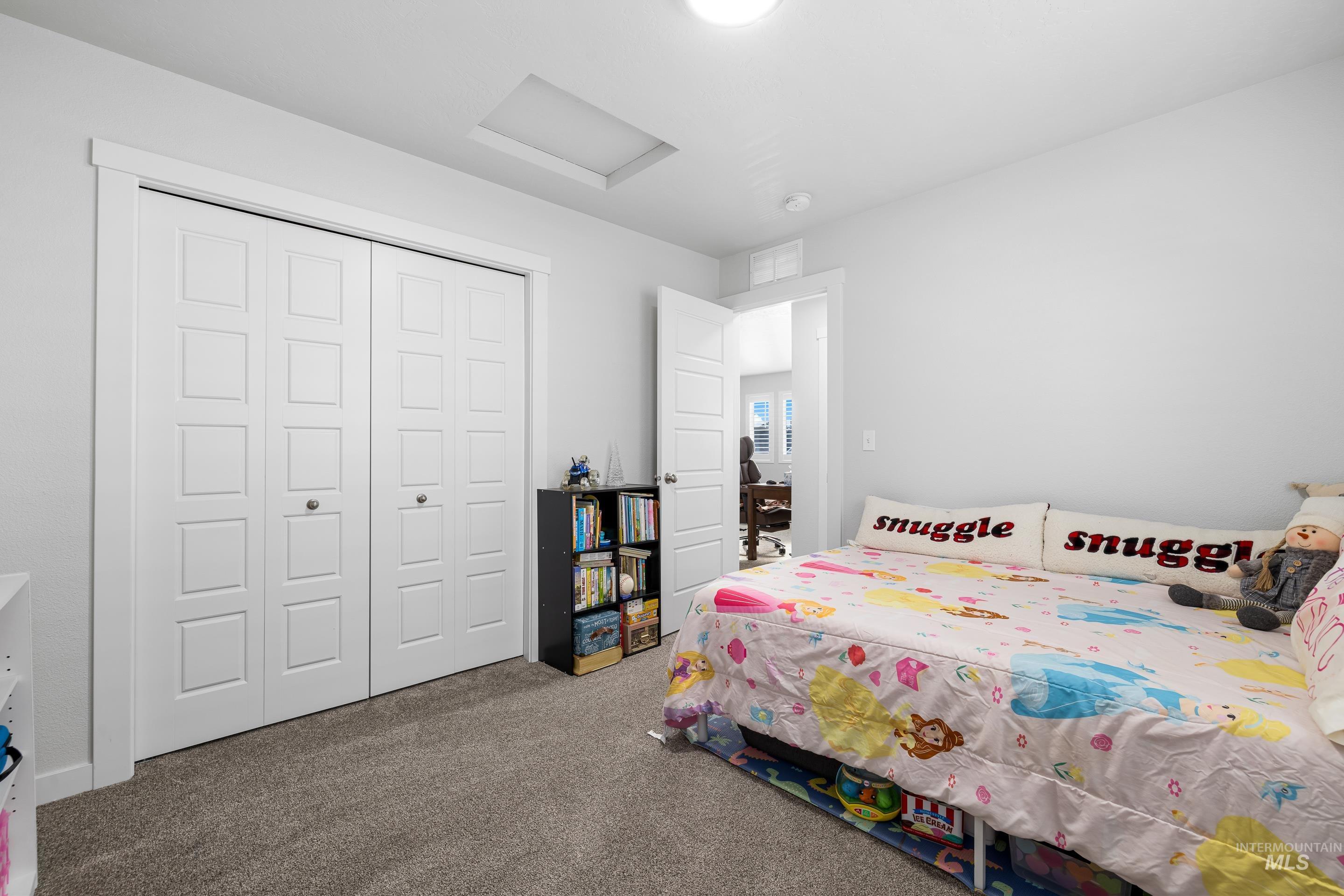 Bedroom with attic access, carpet flooring, and a closet