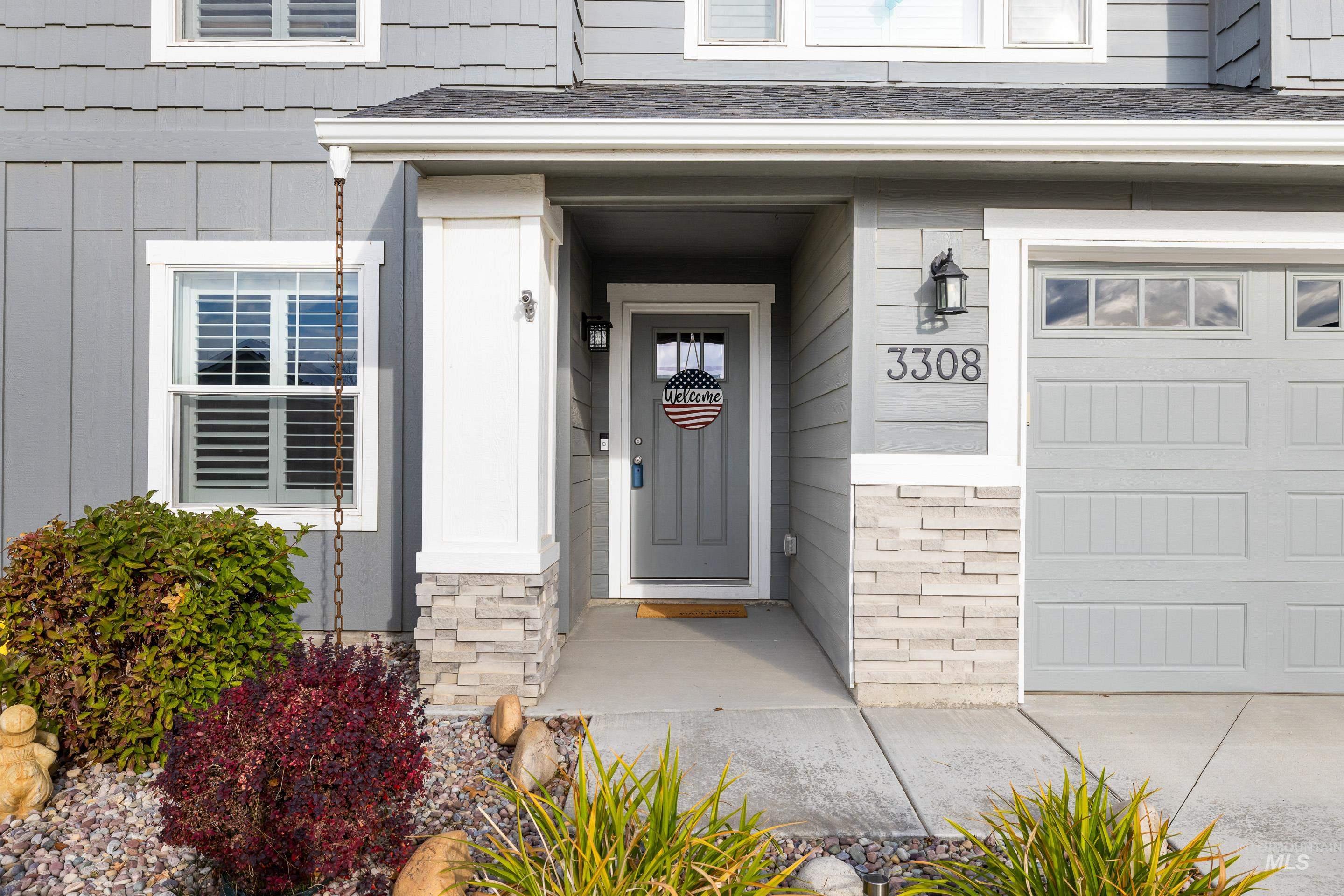 View of exterior entry with a garage, roof with shingles, and stone siding