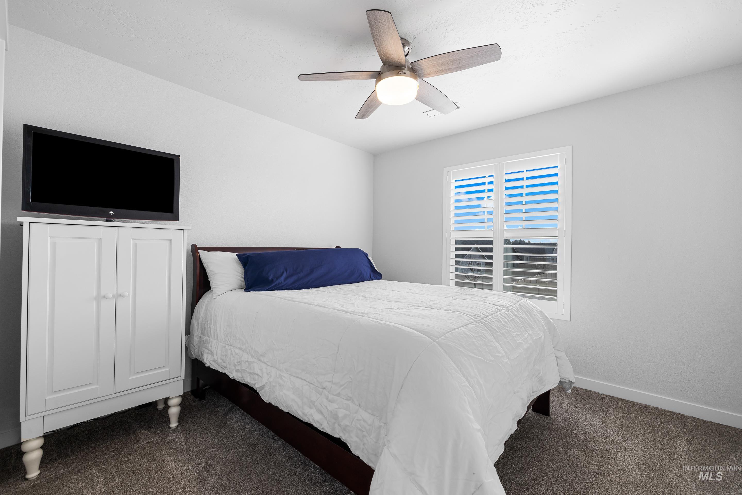 Bedroom featuring dark carpet and ceiling fan
