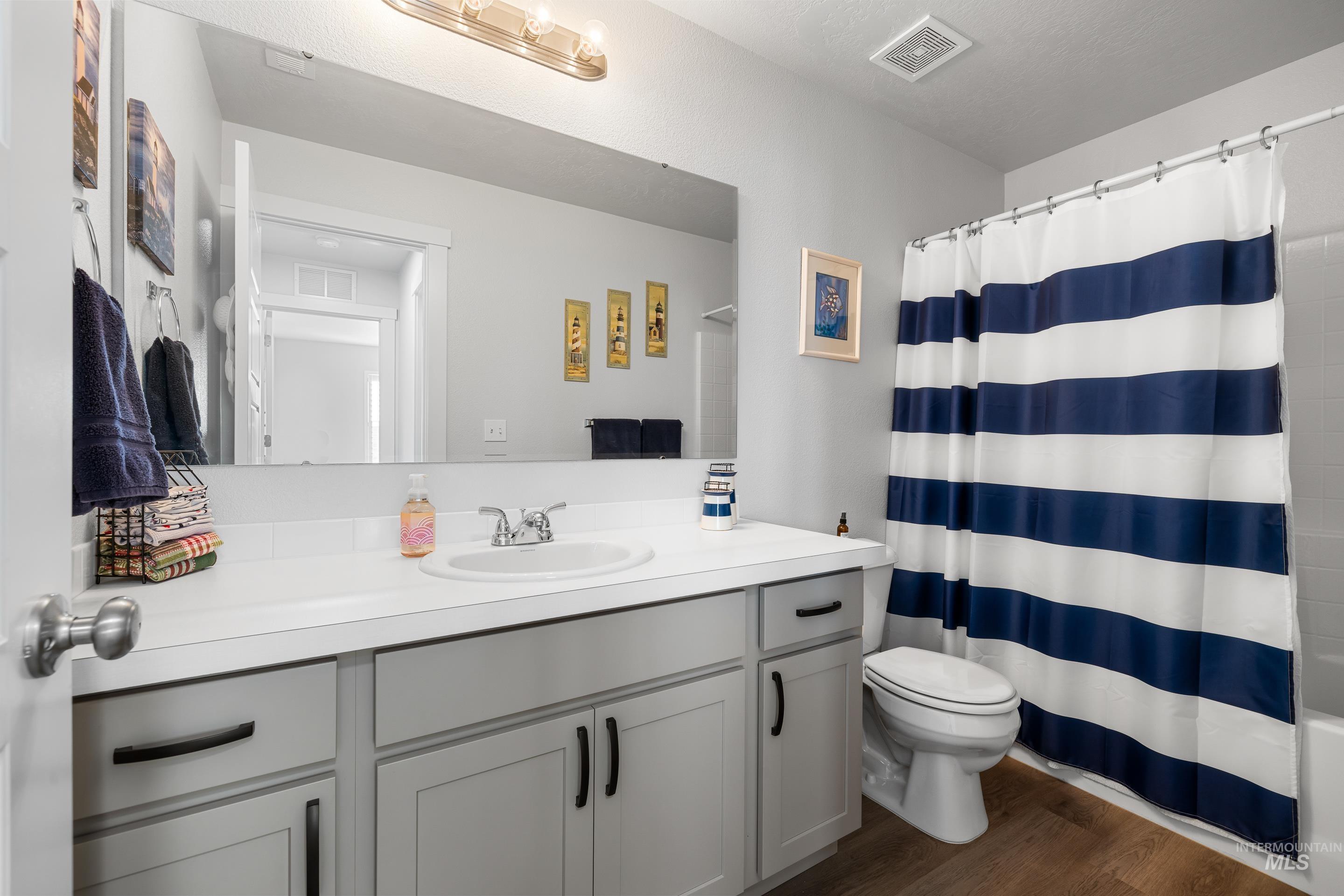 Bathroom featuring vanity, dark wood-type flooring, and shower / bath combo