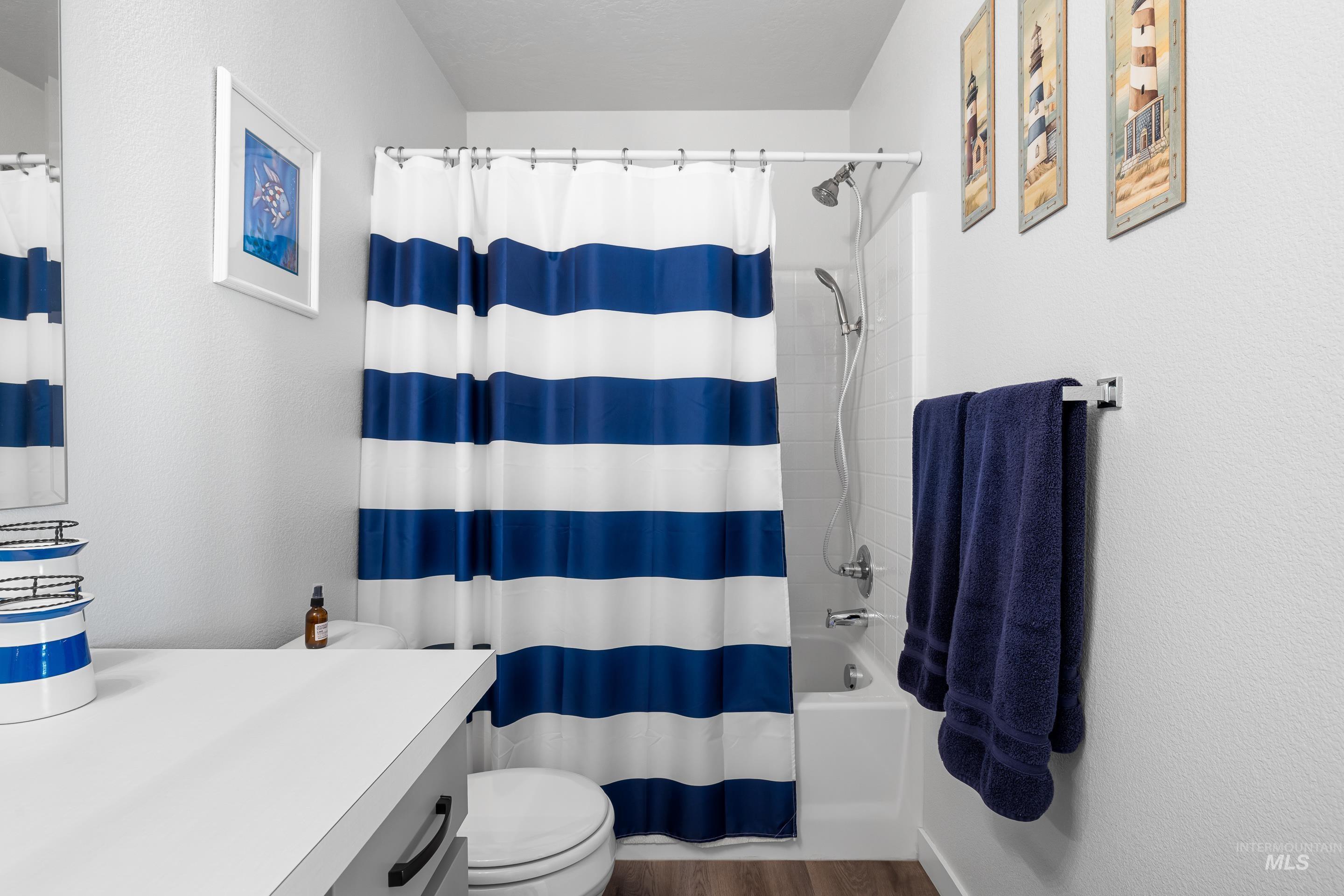 Full bathroom with vanity, shower / bath combo with shower curtain, and dark wood-style flooring