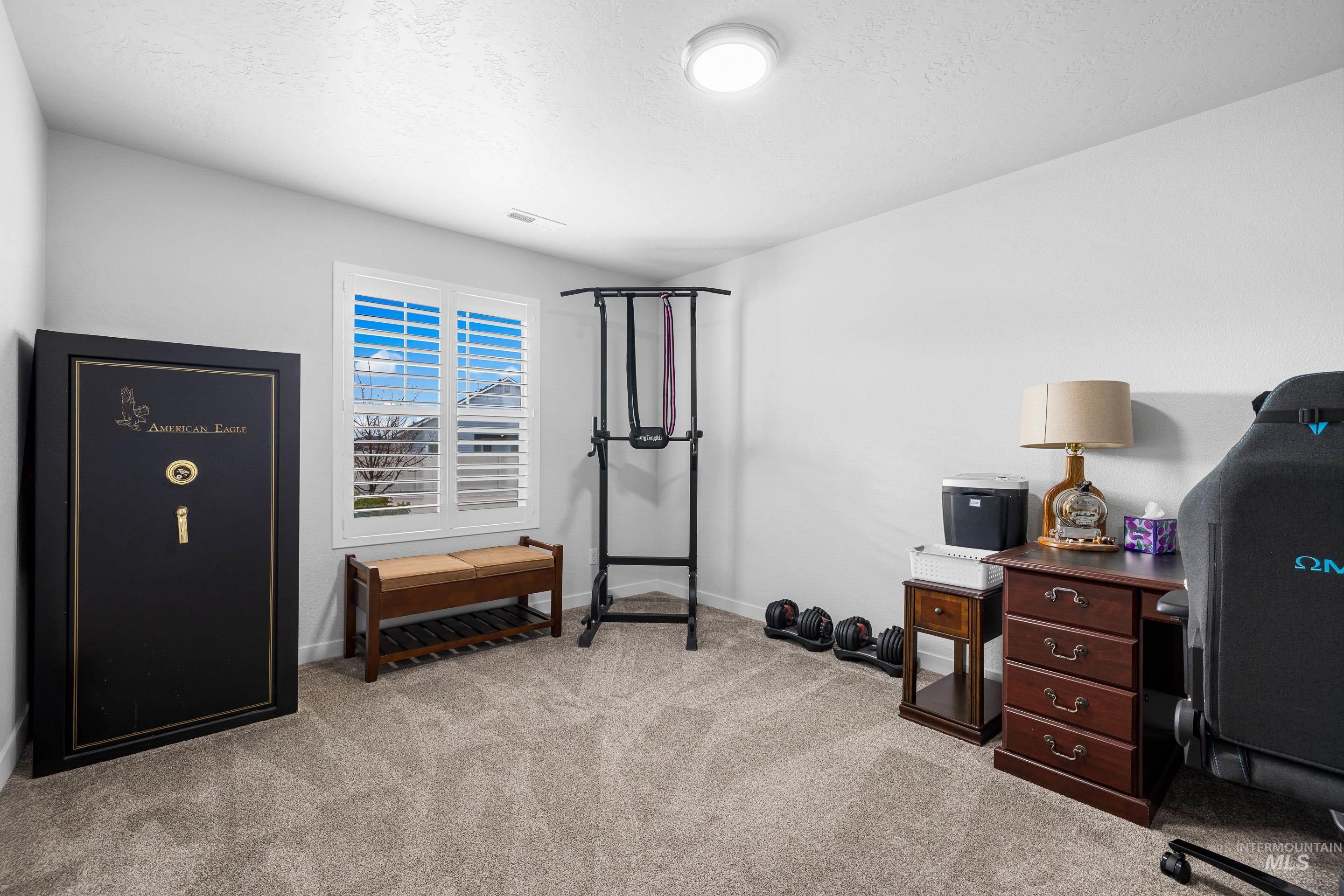 Workout area featuring light colored carpet and a textured ceiling