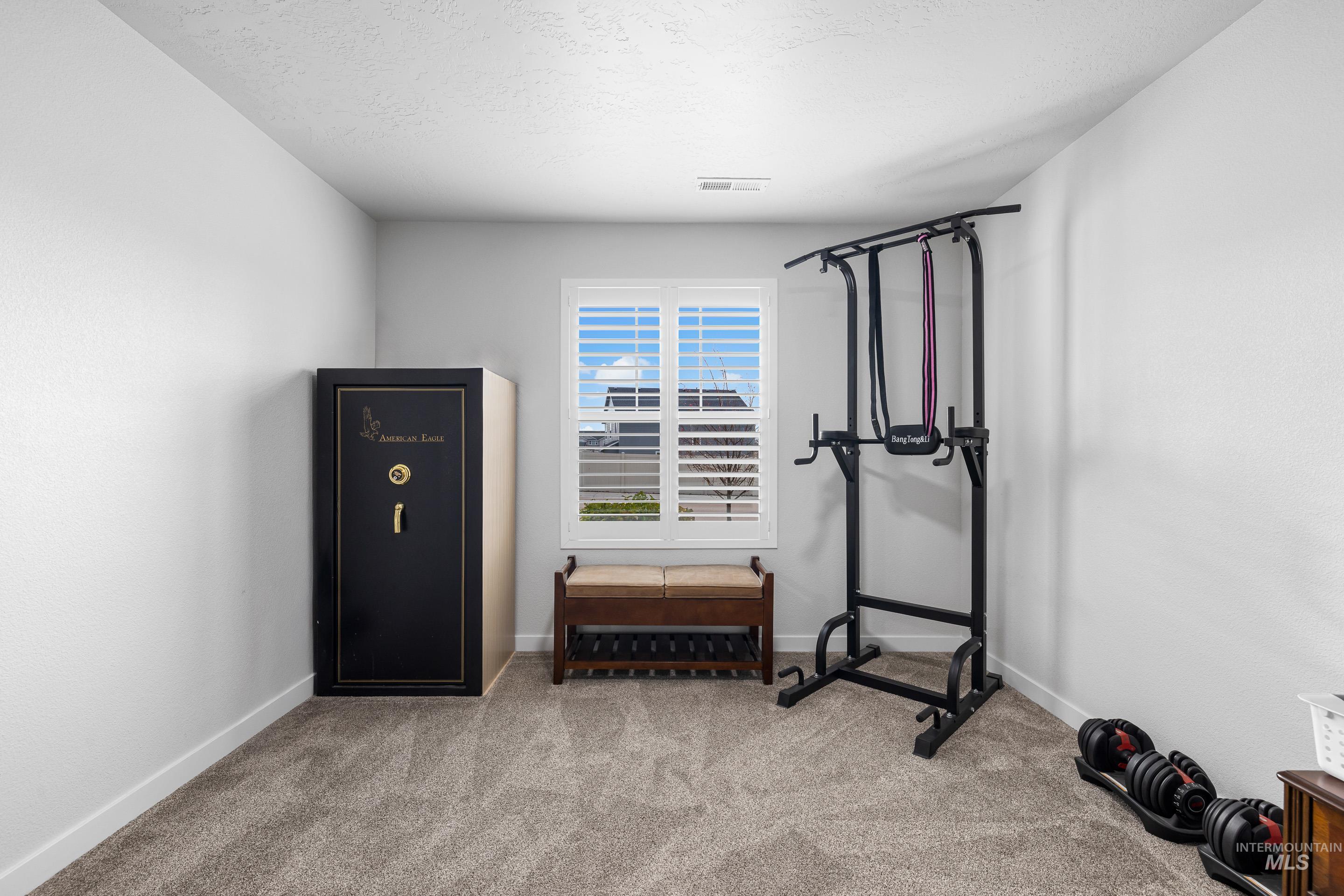 Exercise area featuring light carpet and a textured ceiling