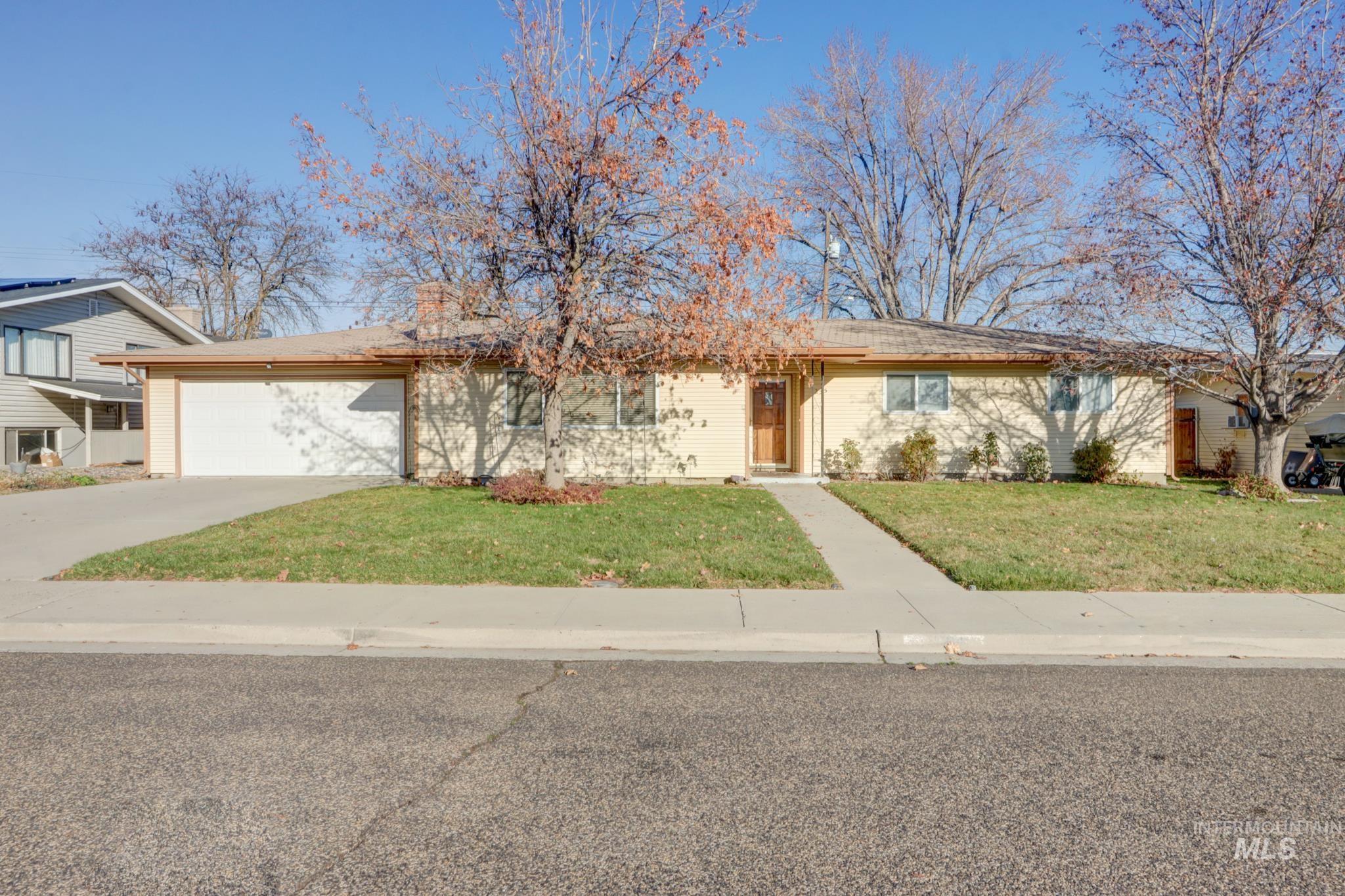 Ranch-style house with a front yard, concrete driveway, an attached garage, and brick siding