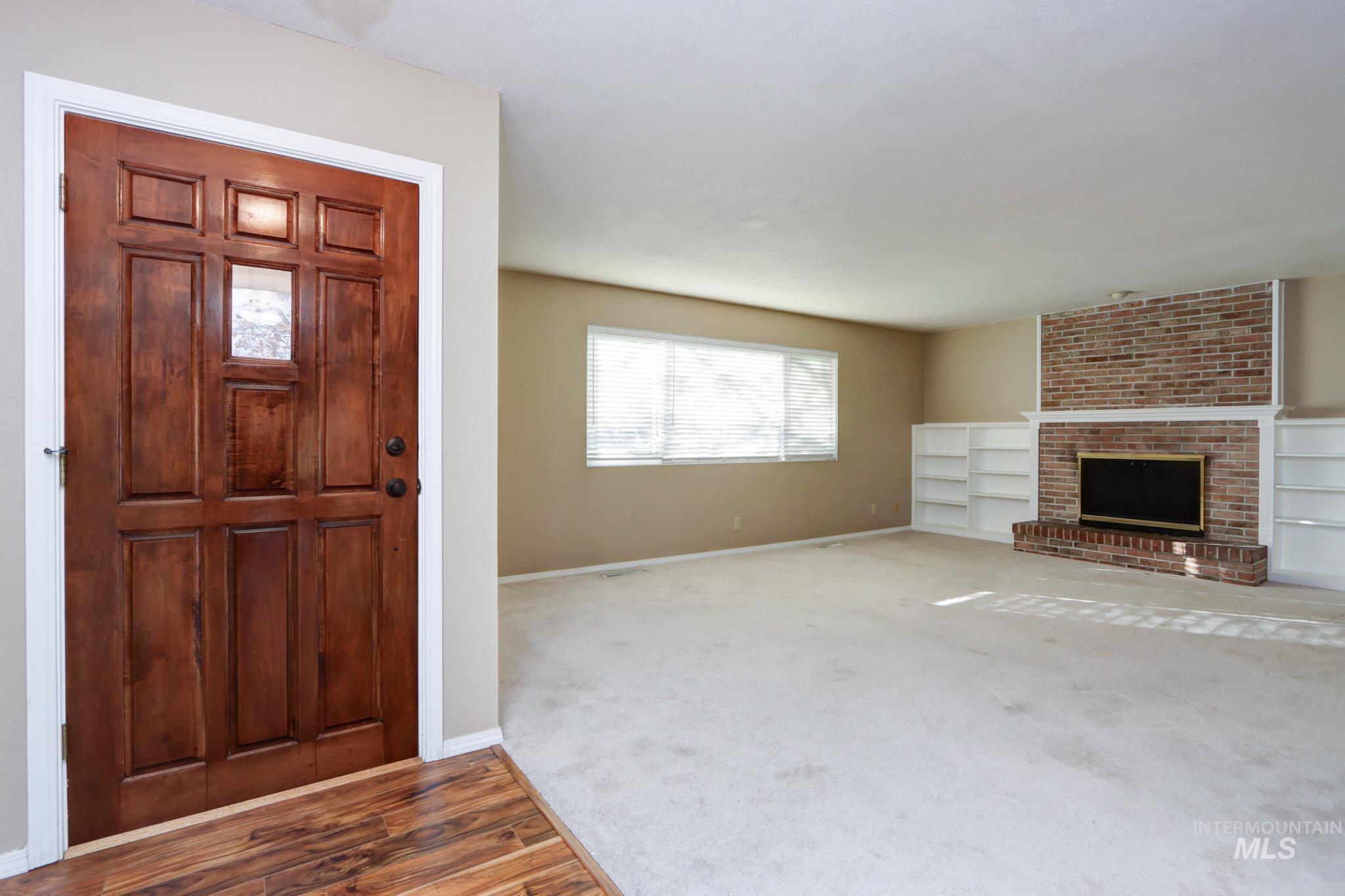 Foyer entrance with a fireplace, wood finished floors, and carpet floors