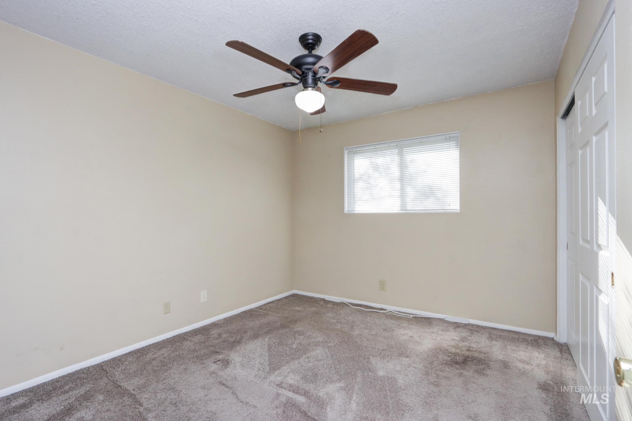 Unfurnished bedroom with a closet, carpet, a ceiling fan, and a textured ceiling
