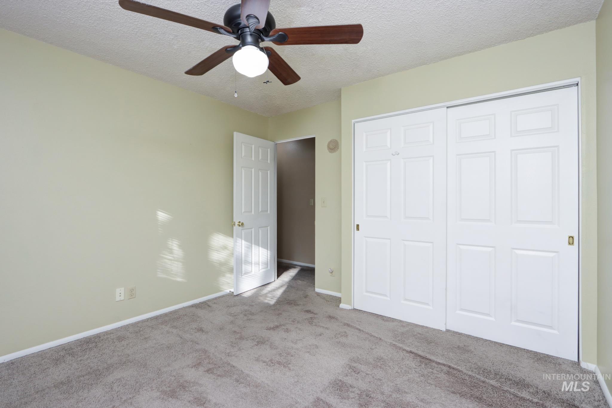 Unfurnished bedroom featuring a textured ceiling, carpet floors, ceiling fan, and a closet