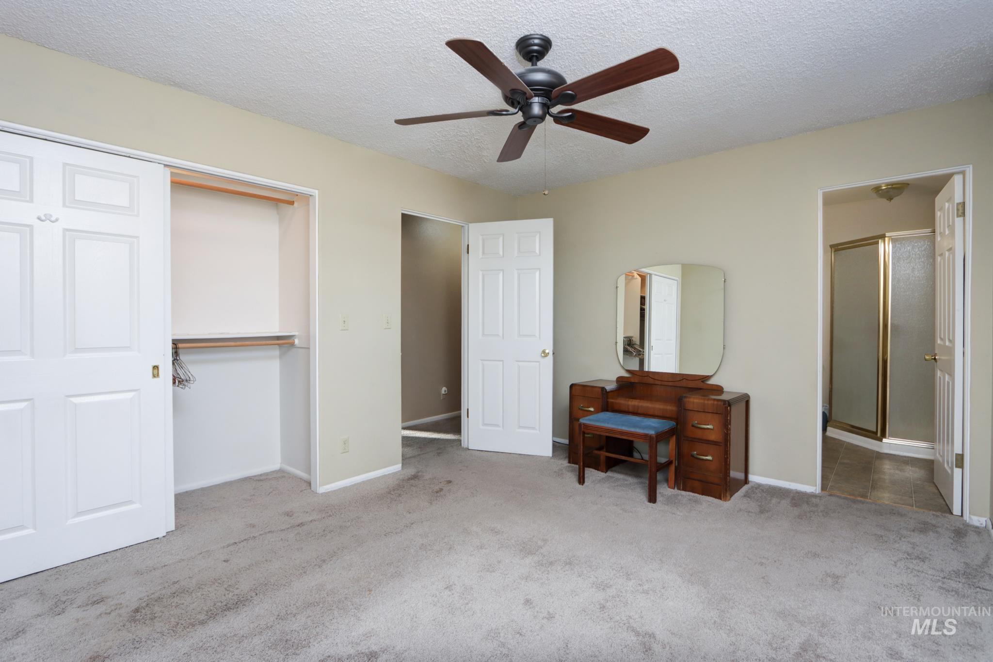 Carpeted bedroom with a textured ceiling, a closet, and a ceiling fan