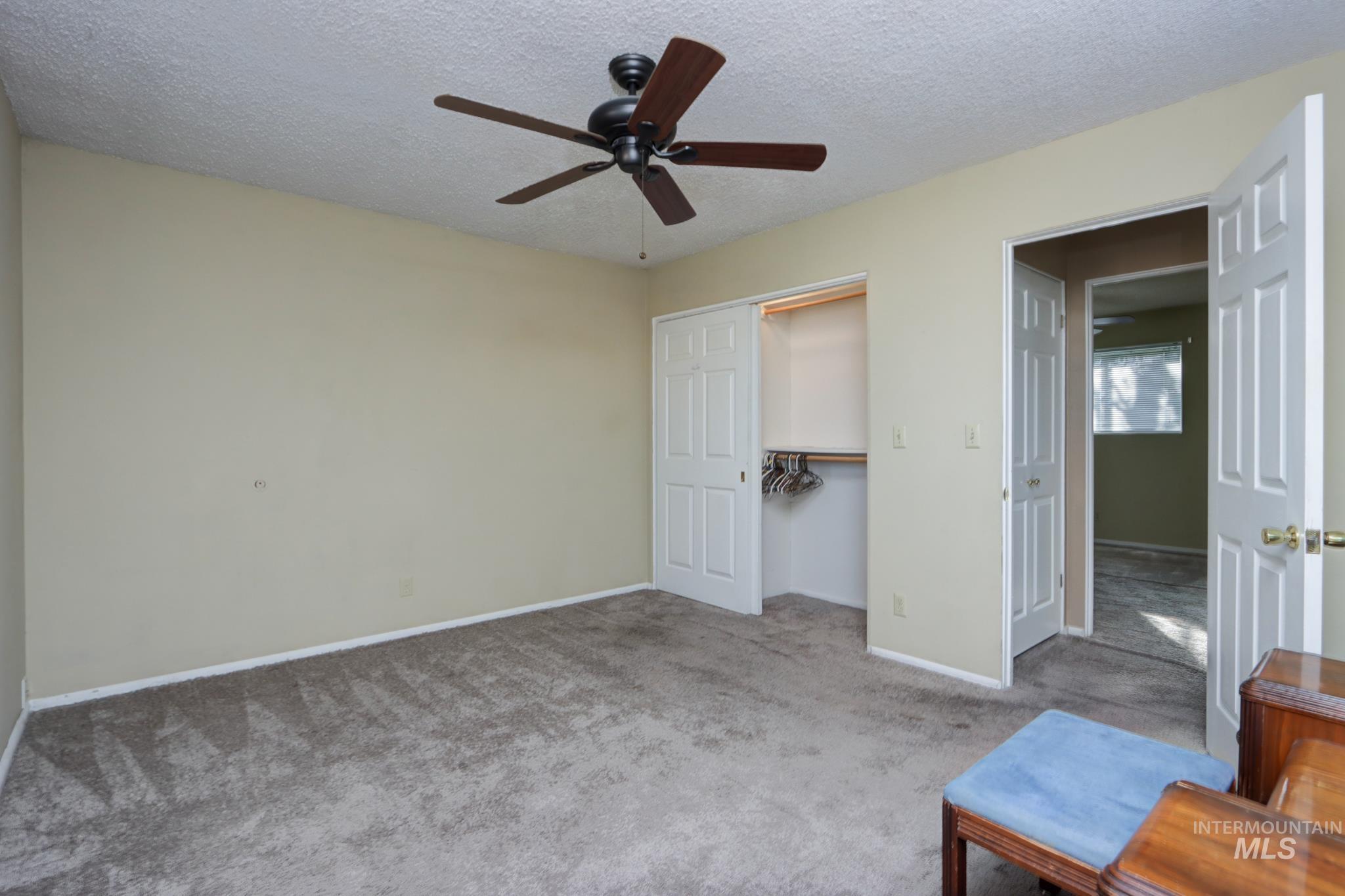 Unfurnished bedroom featuring carpet flooring, a textured ceiling, a closet, and ceiling fan