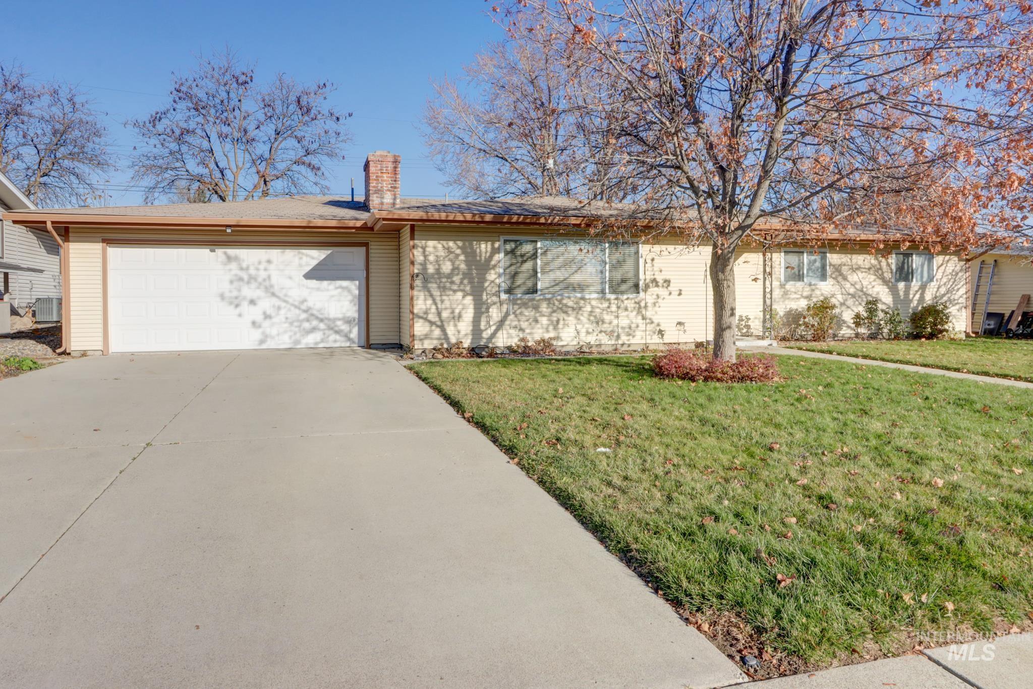 Single story home featuring a front lawn, a chimney, concrete driveway, and a garage