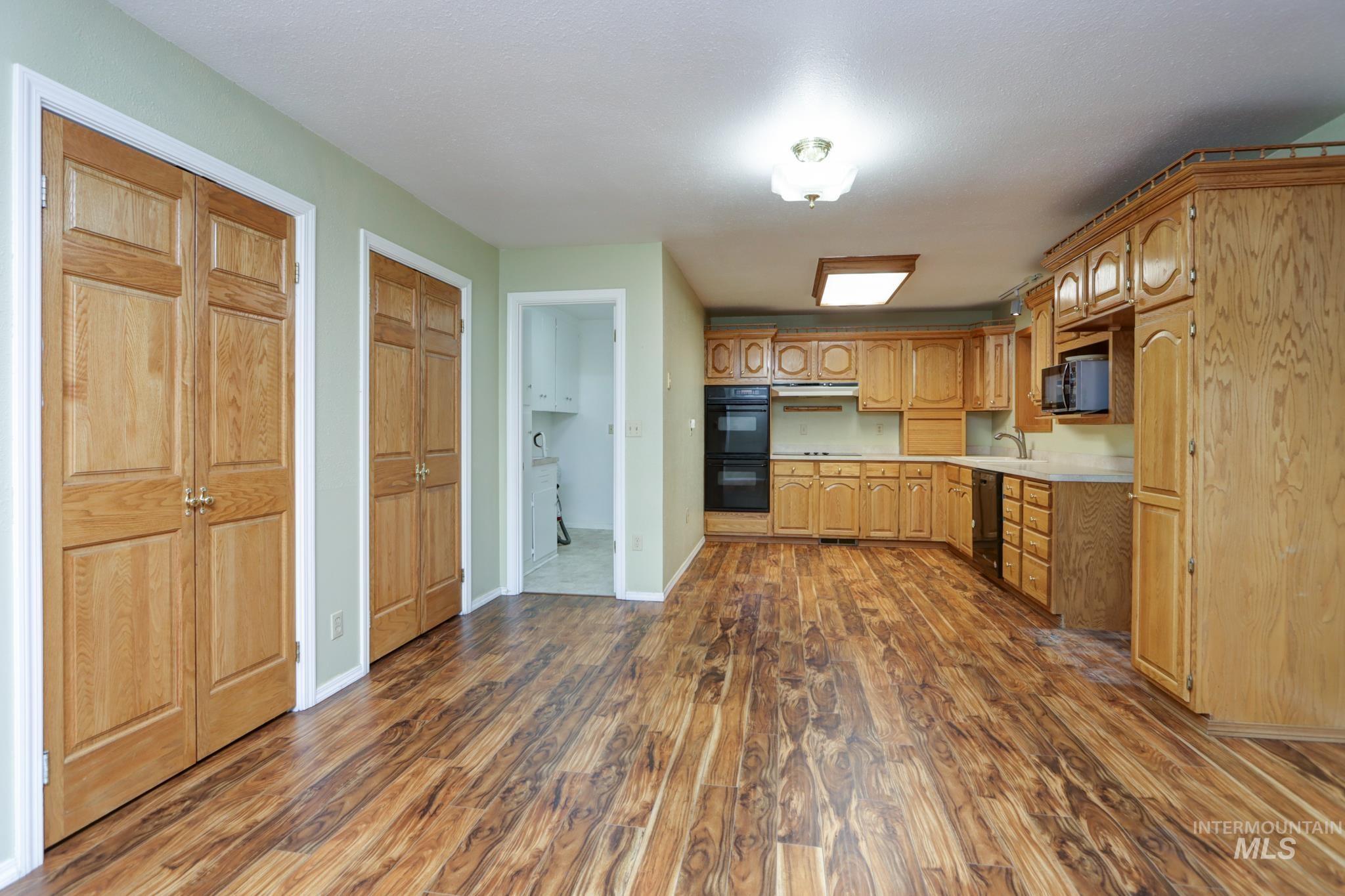 Kitchen with light countertops, dark wood-style floors, and black appliances