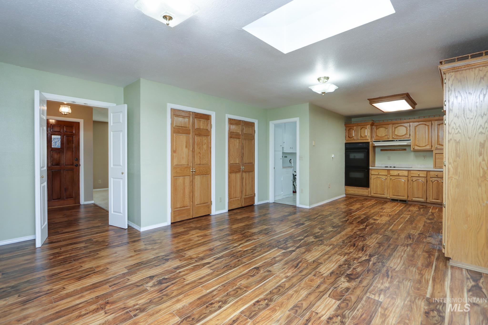 Kitchen featuring a skylight, dark wood finished floors, light countertops, and under cabinet range hood