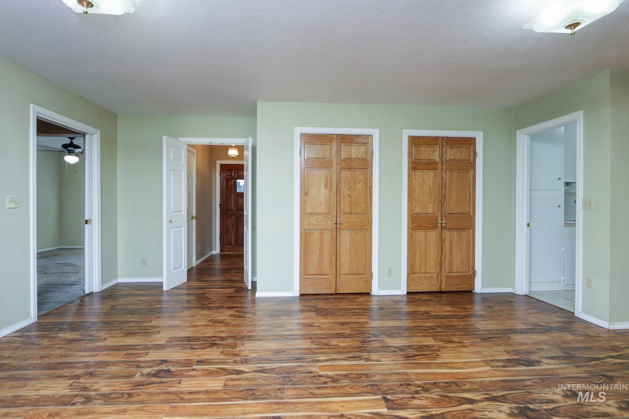Unfurnished bedroom featuring two closets, dark wood-style flooring, and a textured ceiling