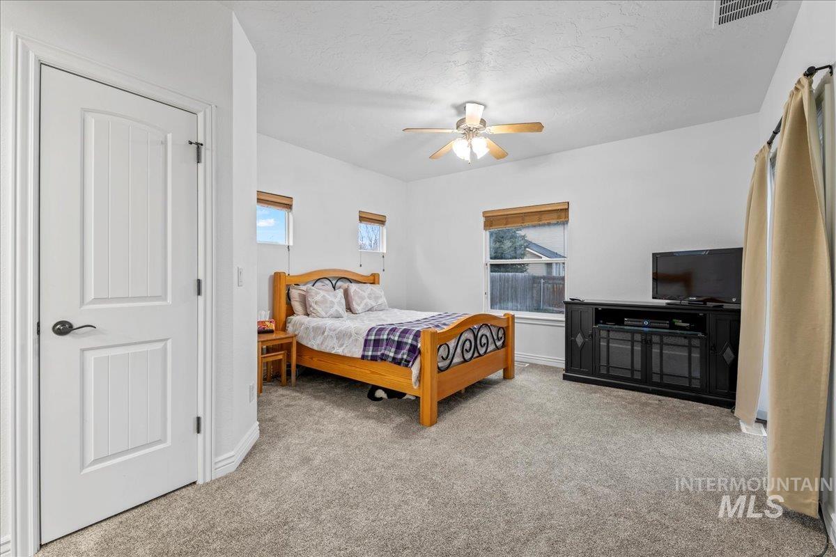 Bedroom featuring light carpet, ceiling fan, and a textured ceiling