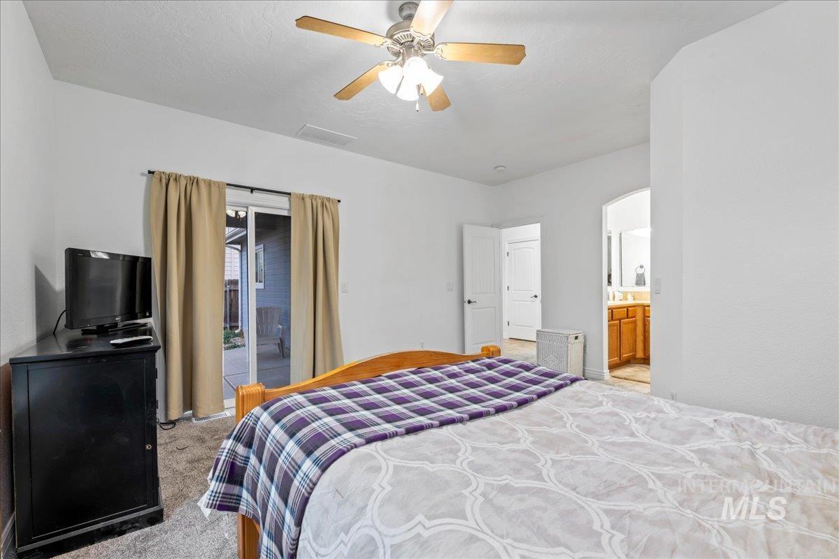 Bedroom featuring carpet flooring, ensuite bath, a ceiling fan, and access to exterior