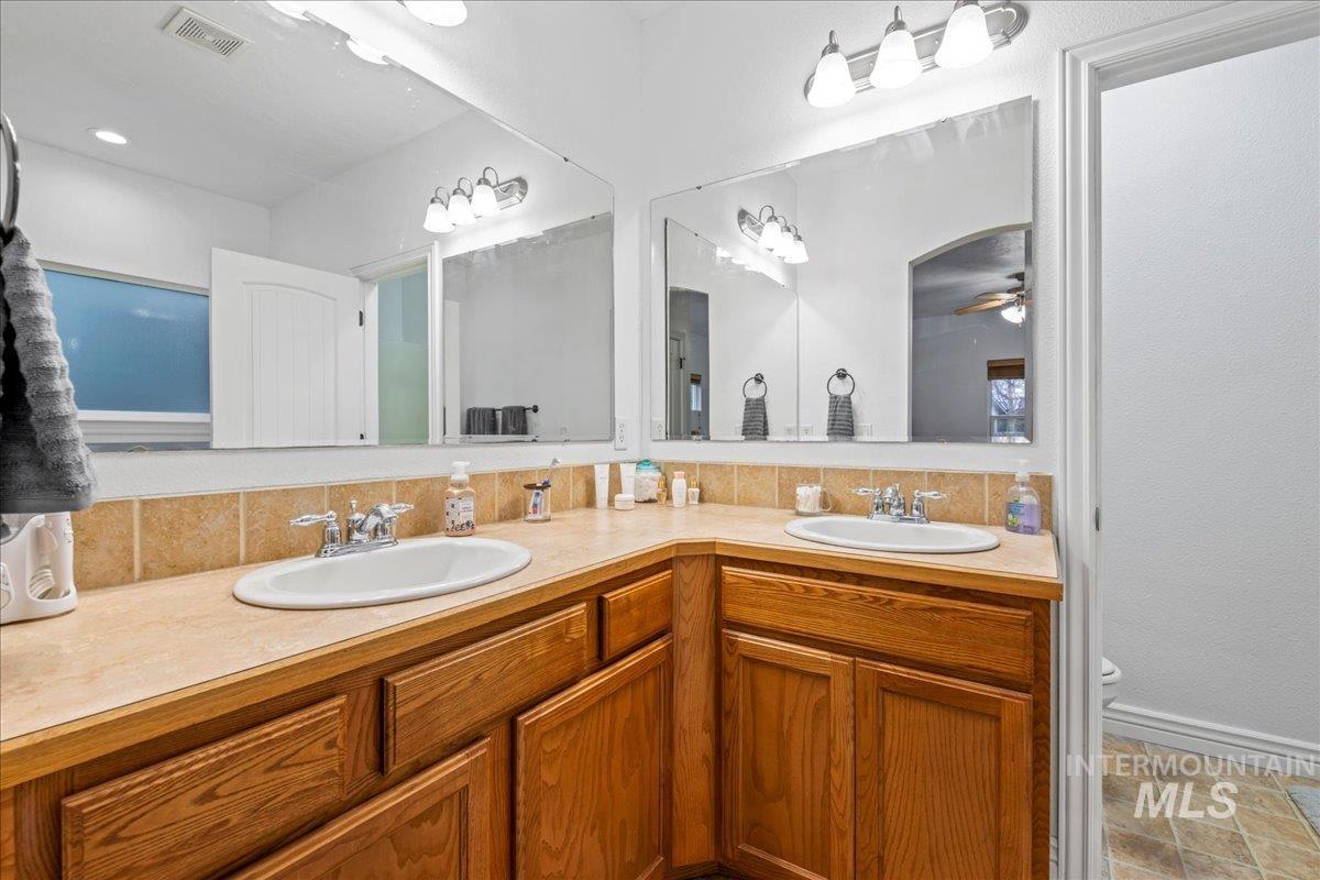 Full bathroom featuring double vanity and ceiling fan
