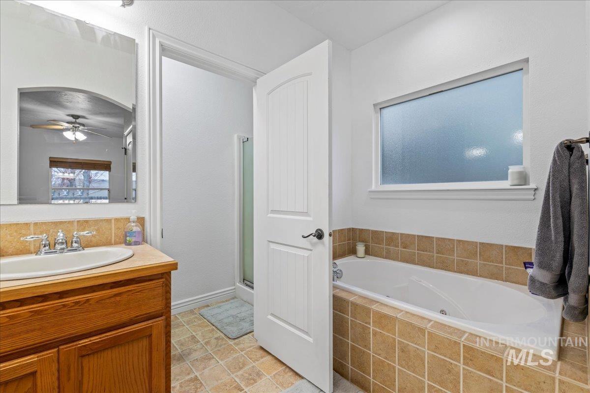 Bathroom with a stall shower, a bath, vanity, and a ceiling fan