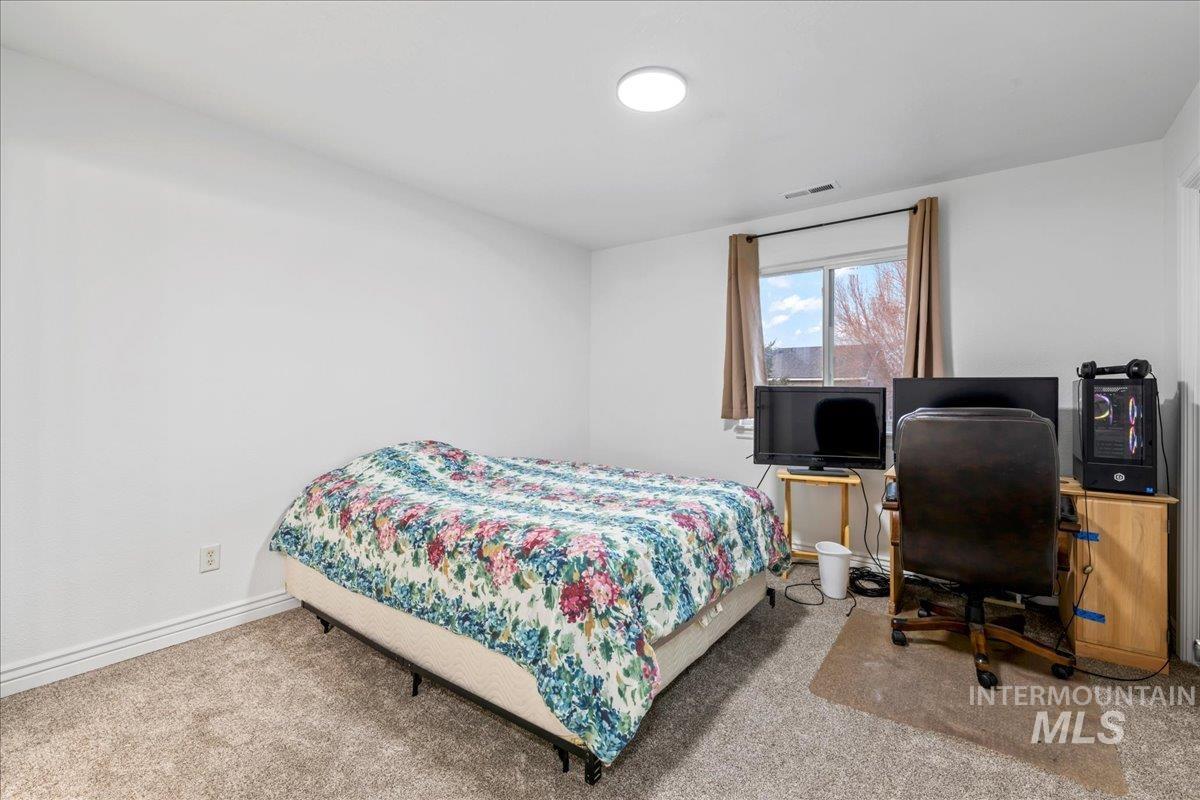Carpeted bedroom featuring an office area and baseboards