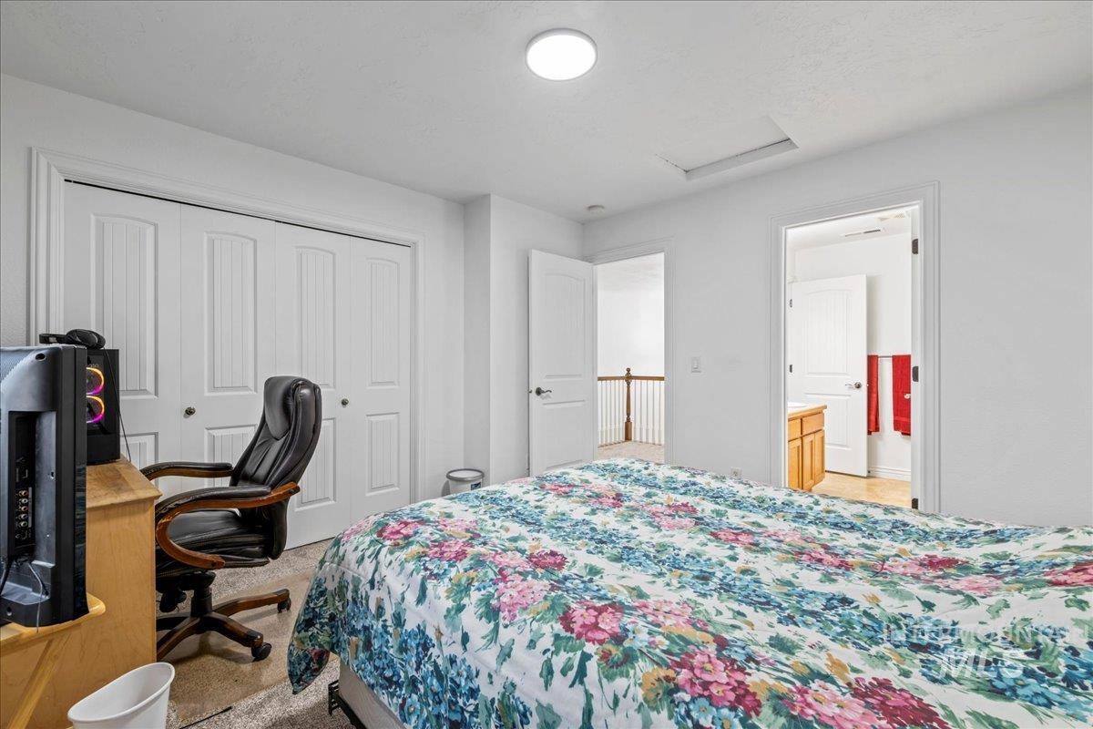 Bedroom featuring attic access, light carpet, a closet, ensuite bath, and an office area