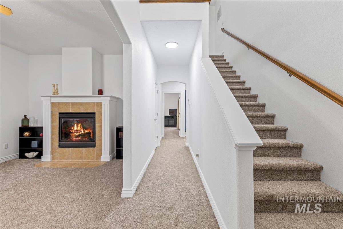 Hallway with carpet floors, stairway, and arched walkways