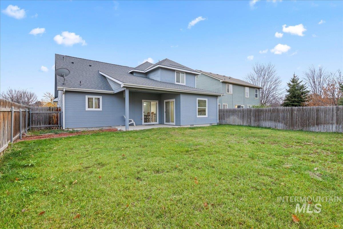 Back of property with a patio, a fenced backyard, and a shingled roof