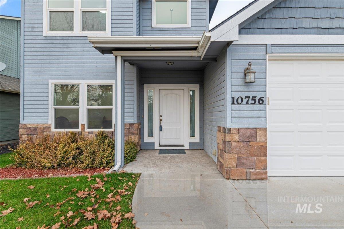 Property entrance featuring stone siding and a garage