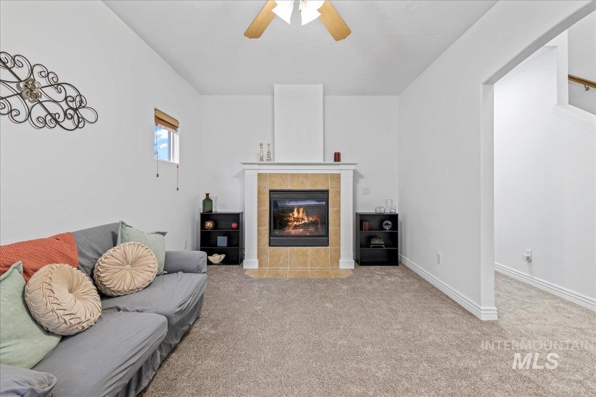 Carpeted living room featuring a fireplace and ceiling fan