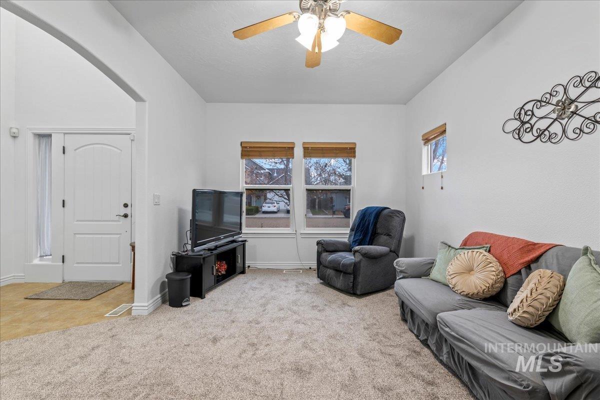 Living area featuring carpet floors, healthy amount of natural light, and ceiling fan