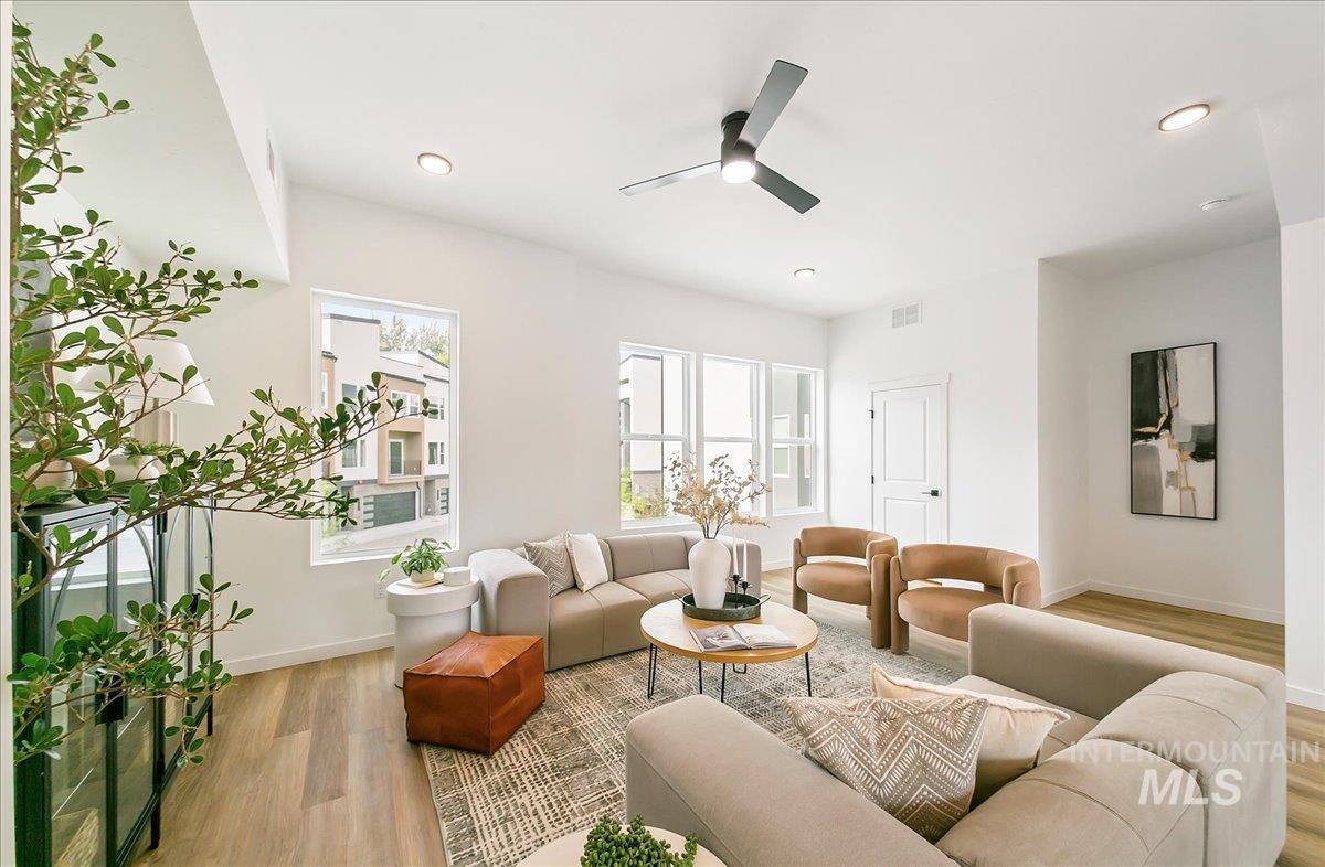 Living area featuring light wood-style flooring, a ceiling fan, and recessed lighting
