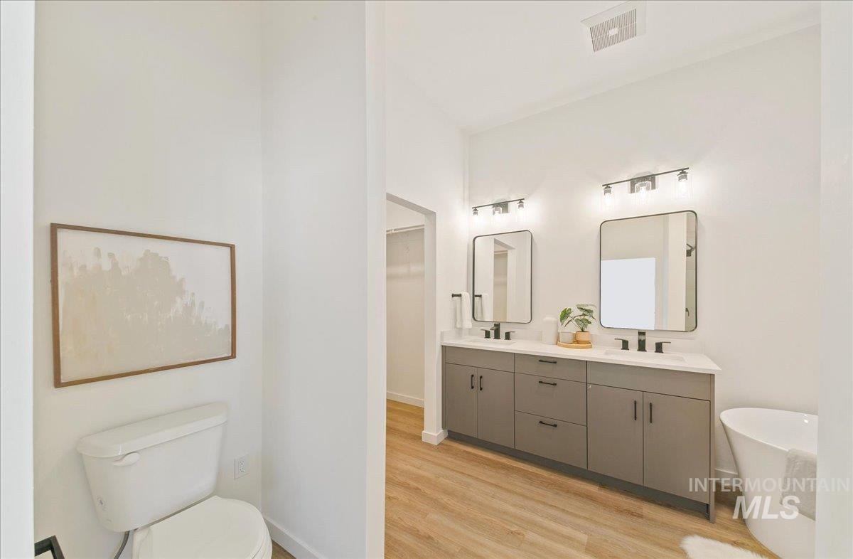 Full bath with a freestanding tub, double vanity, and light wood-style floors